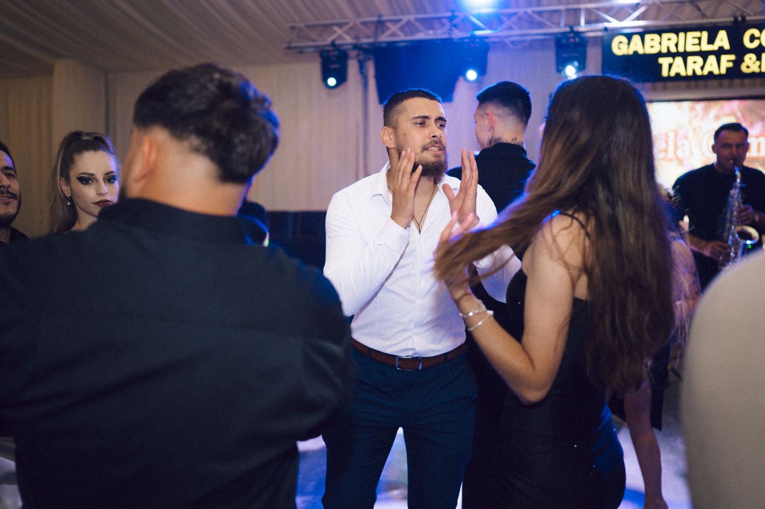 People dancing together at a nightclub or party venue with blue lighting effects in the background.