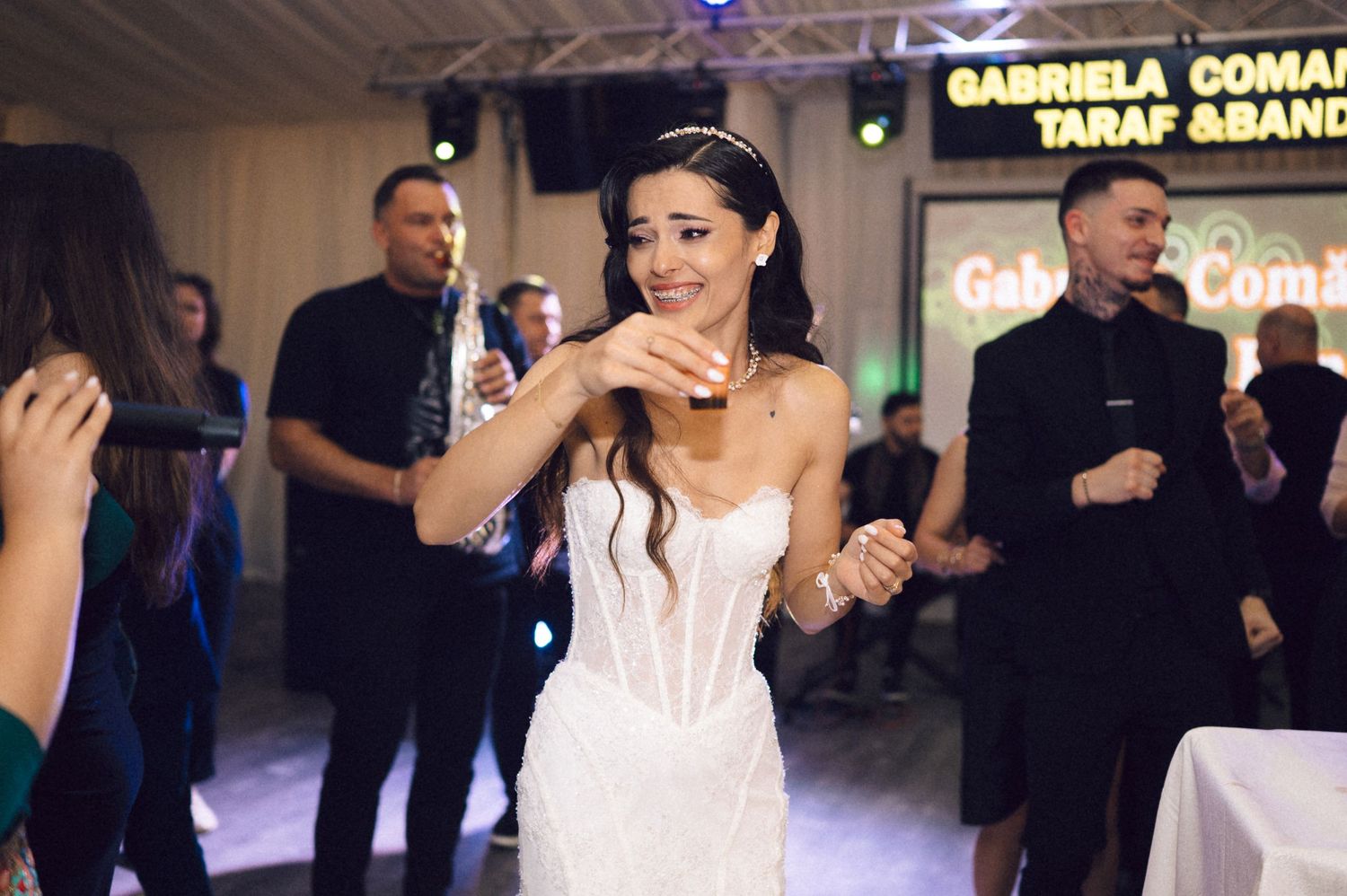 Wedding guests dance and celebrate during an evening reception with colorful lighting and festive atmosphere.