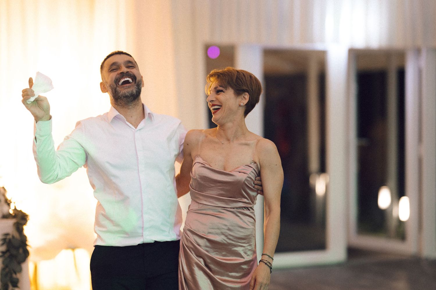 Joyful celebration on the dance floor at an elegant indoor wedding reception with warm lighting.