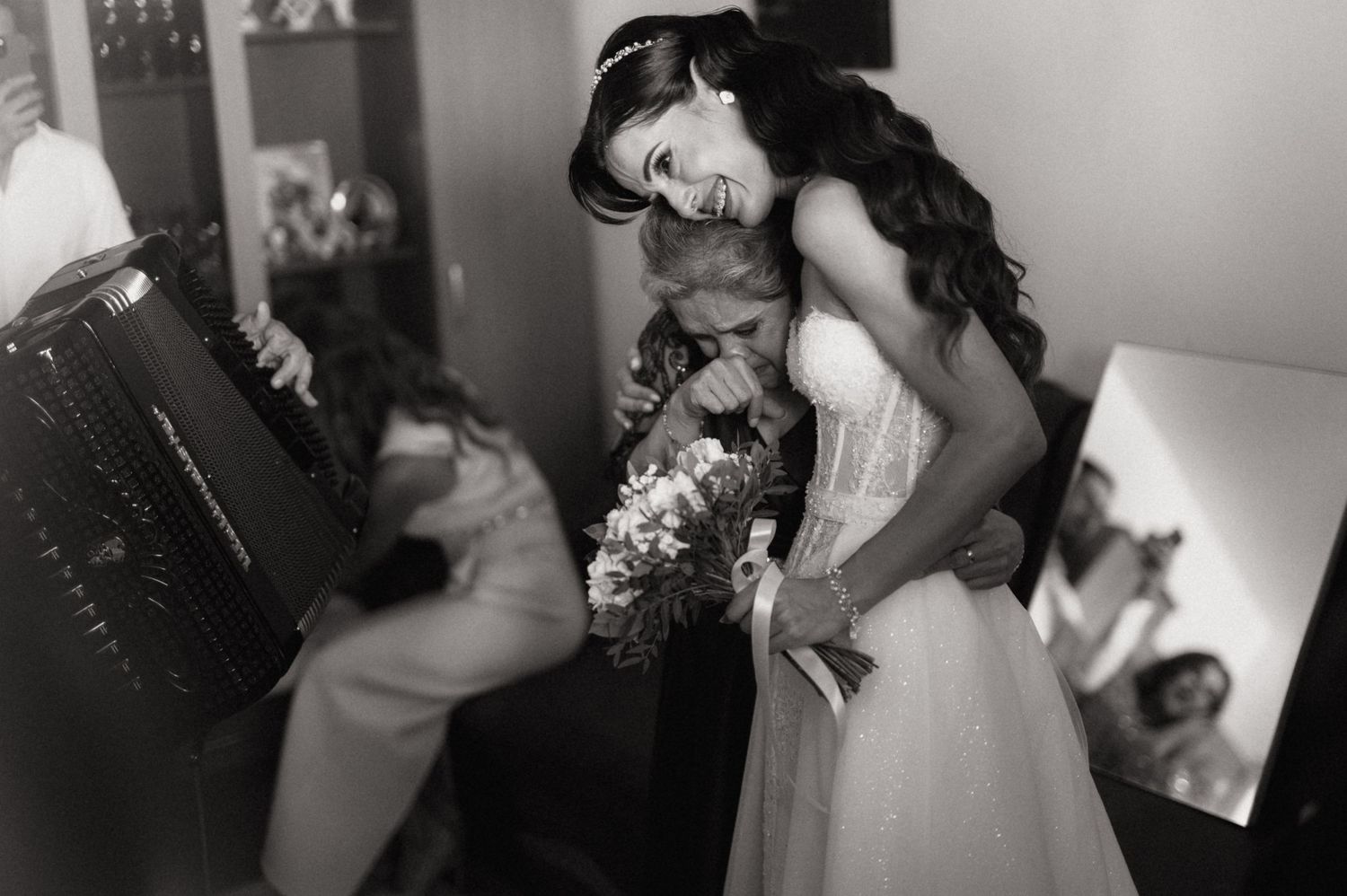 A bride in a white wedding dress leans down while getting ready in an intimate black and white moment.