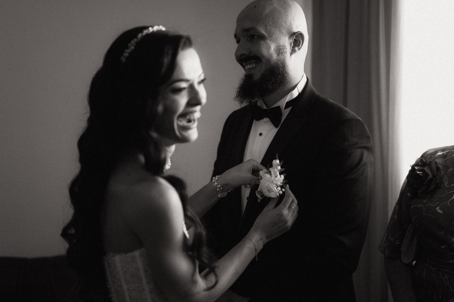 A black and white wedding photo showing a couple sharing an intimate moment as they prepare for their ceremony.