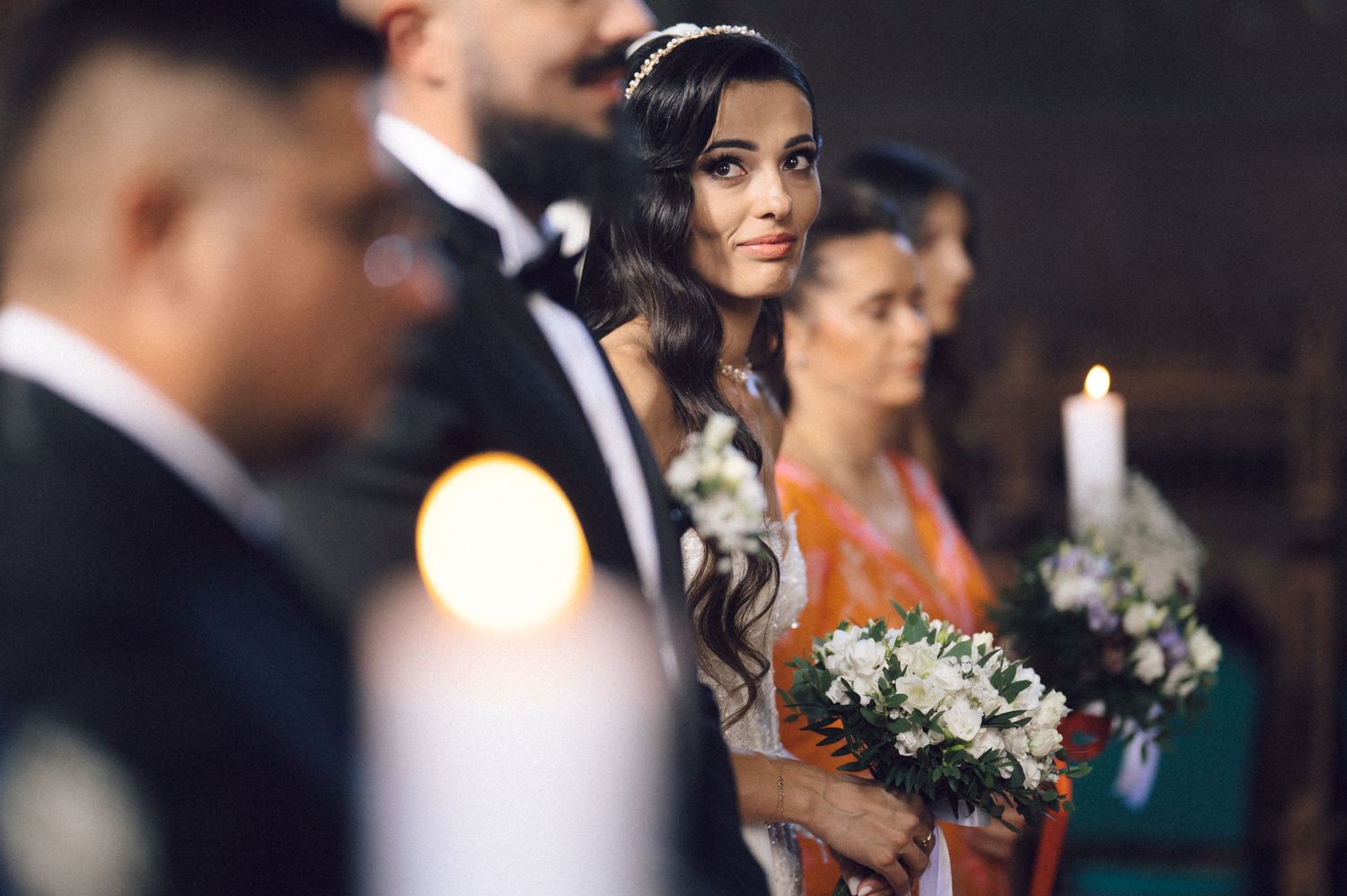 Wedding guests mingle during an elegant reception while holding white floral bouquets and wearing formal attire.