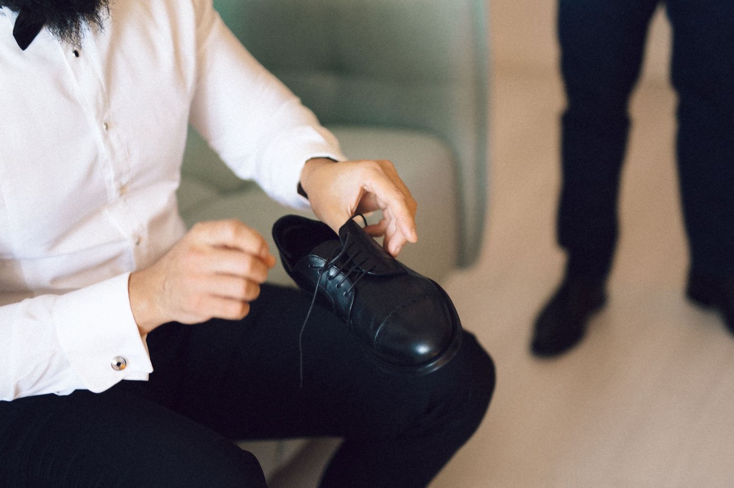 Close-up view of hands adjusting a black bow tie against a white dress shirt.