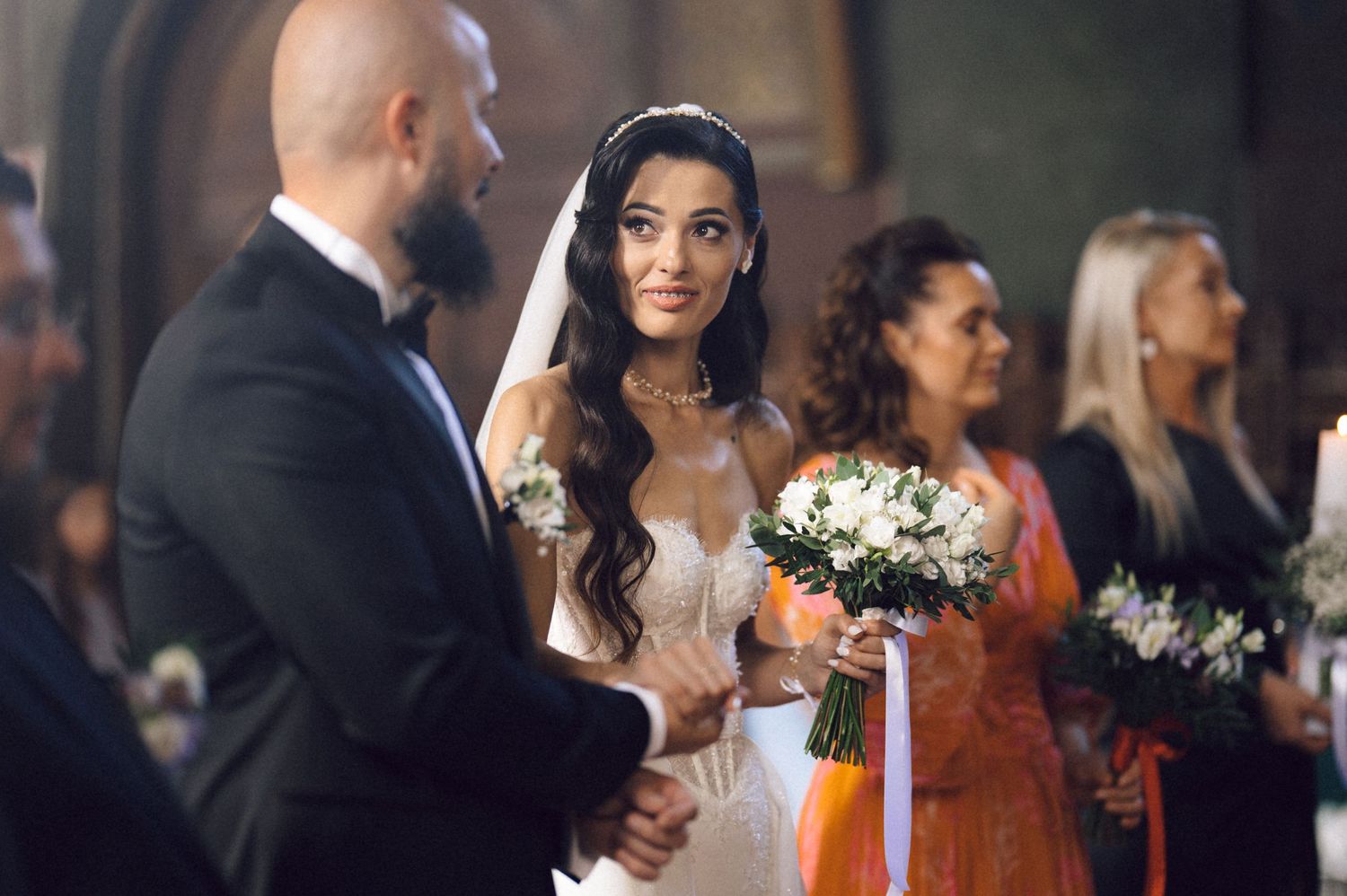 Wedding guests celebrate during a joyful reception as they gather around tables in an elegant indoor venue.