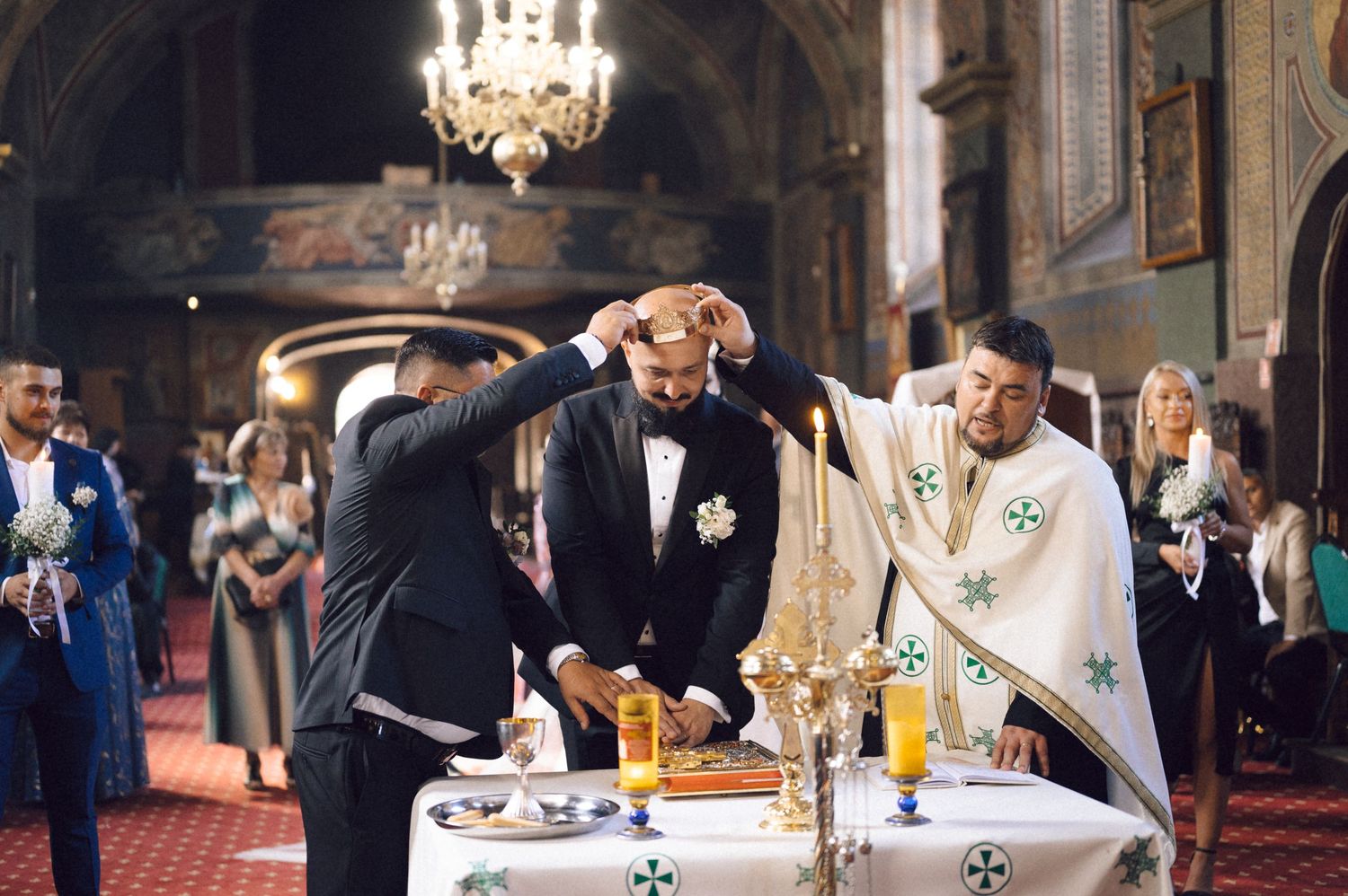 Religious ceremony taking place in an ornate church with priest and participant at altar under chandelier lighting.