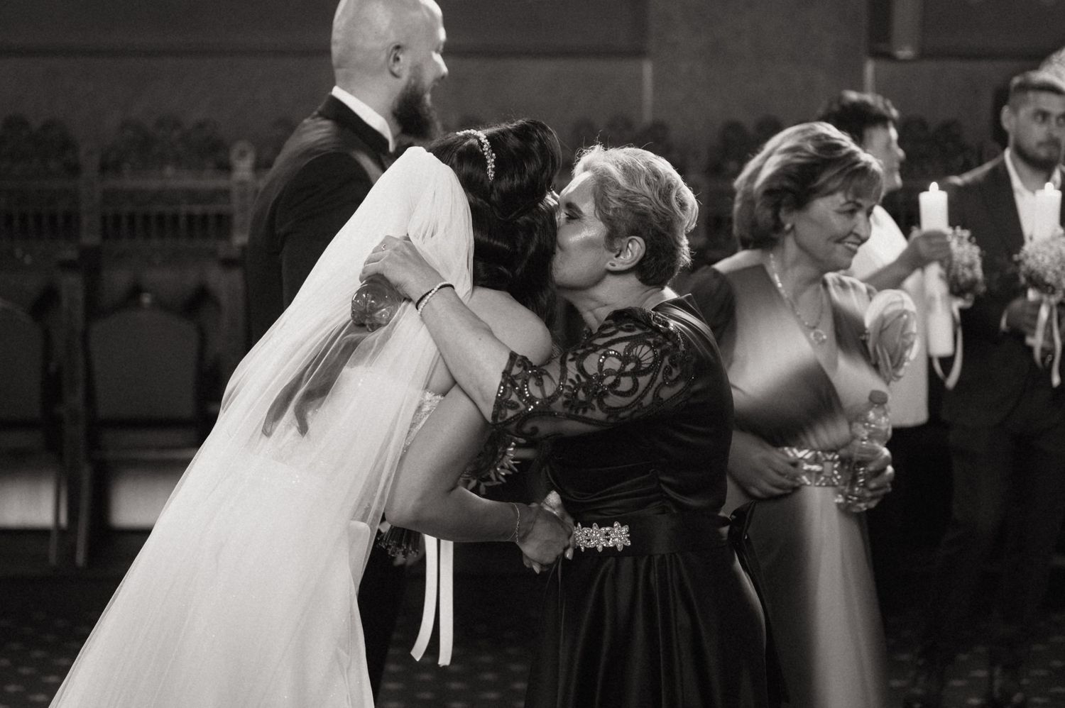 Five black and white wedding photos showing couples sharing romantic kisses during their ceremonies.