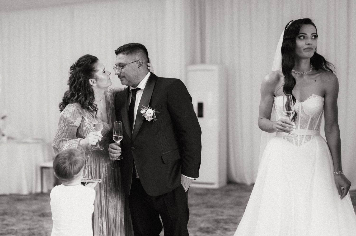 Black and white photo of wedding guests interacting at an elegant indoor reception venue.