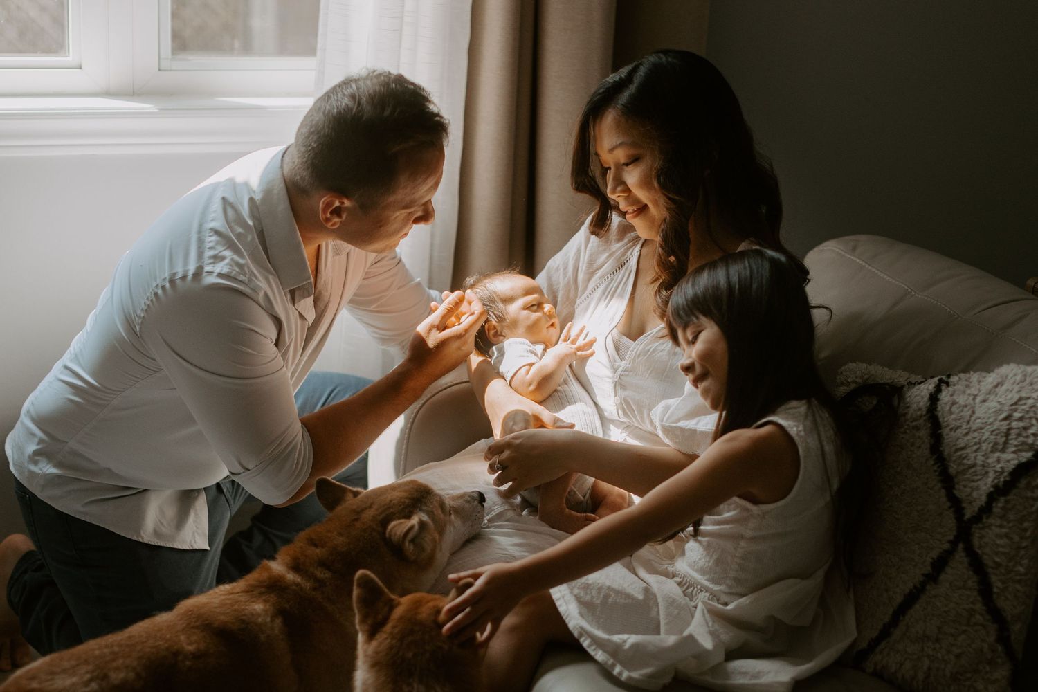A cozy home photography session for a family with a newborn baby and dogs.