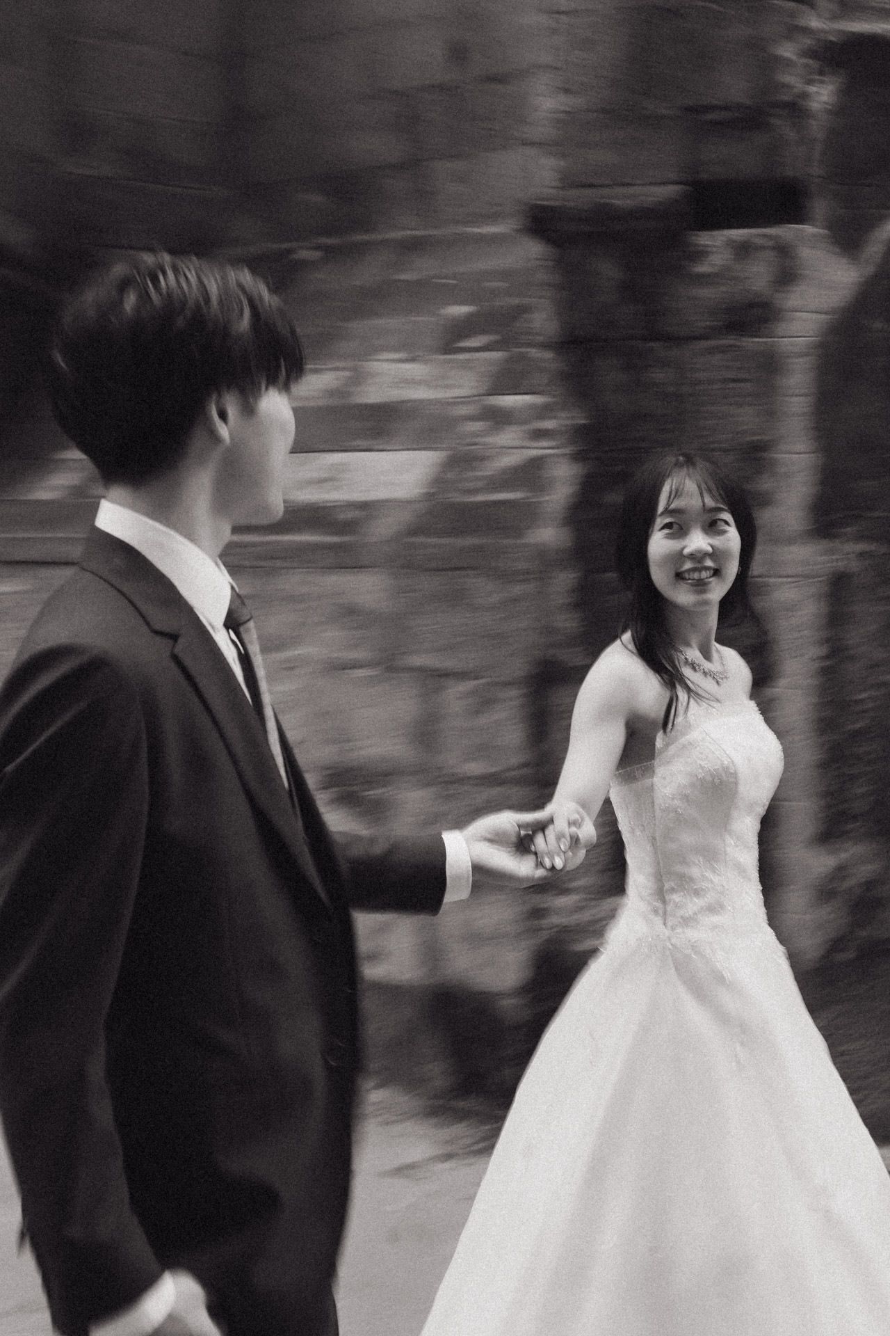 A couple in wedding attire dances together in a black and white photograph.