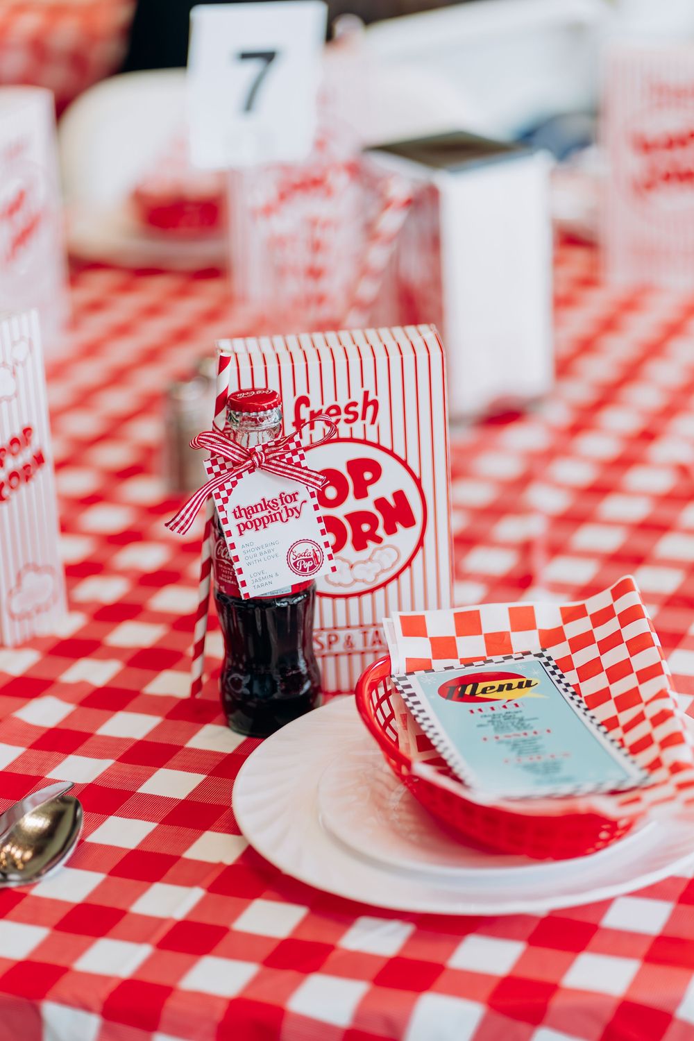 Place settings with red checkered tablecloth and classic popcorn boxes for retro diner party.