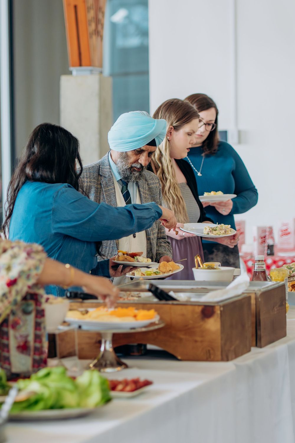 People gathered around a buffet table serving themselves food at a casual event.