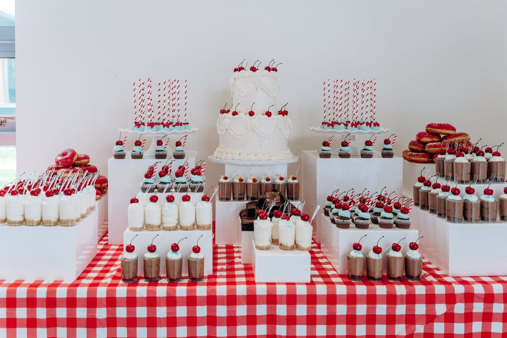 Red and white checkered tablecloth with vintage-style soda bottles and party favors arranged in rows.