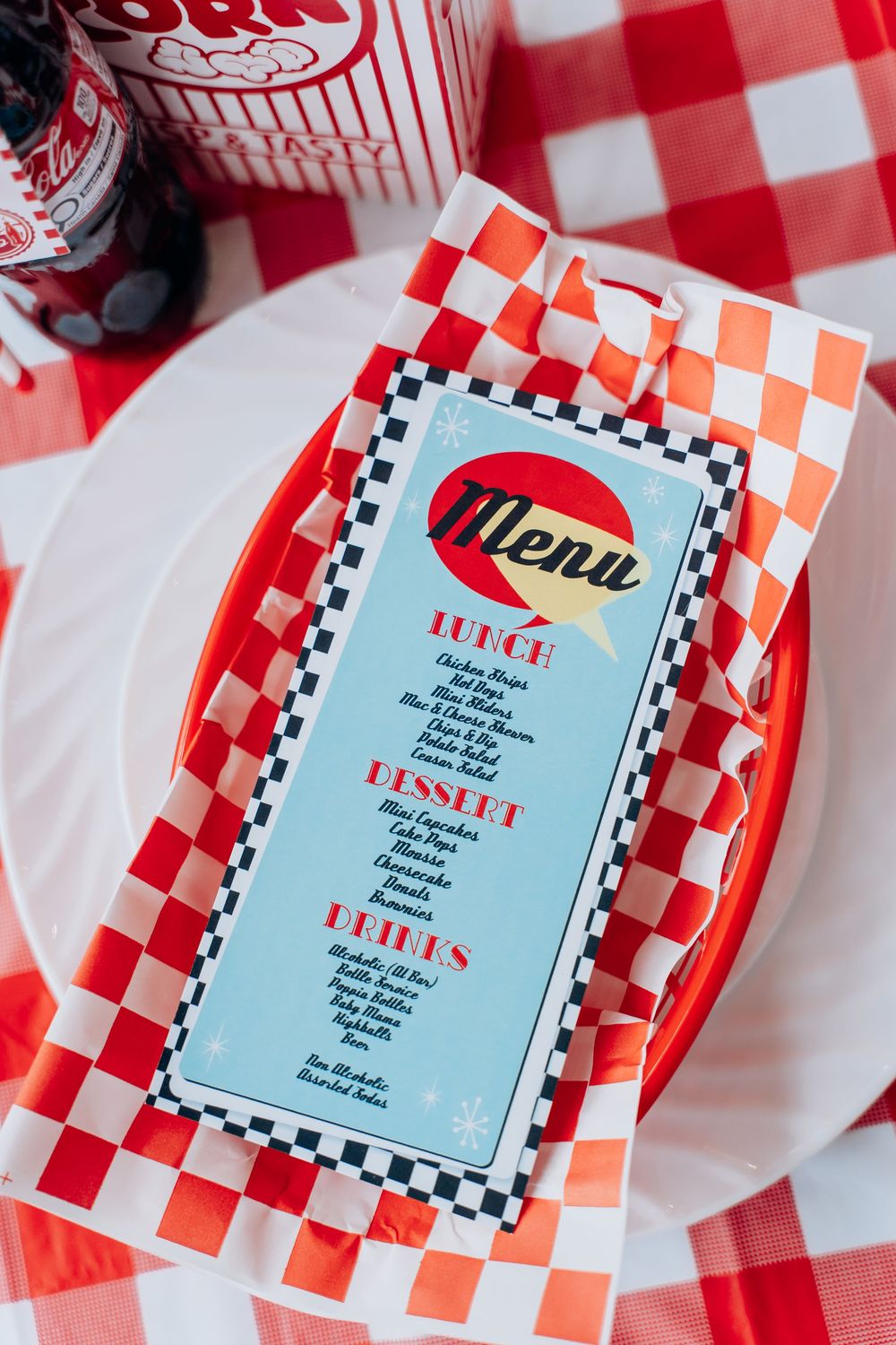 Retro diner menu with red checkered pattern and classic design elements displayed on a table with red gingham cloth.