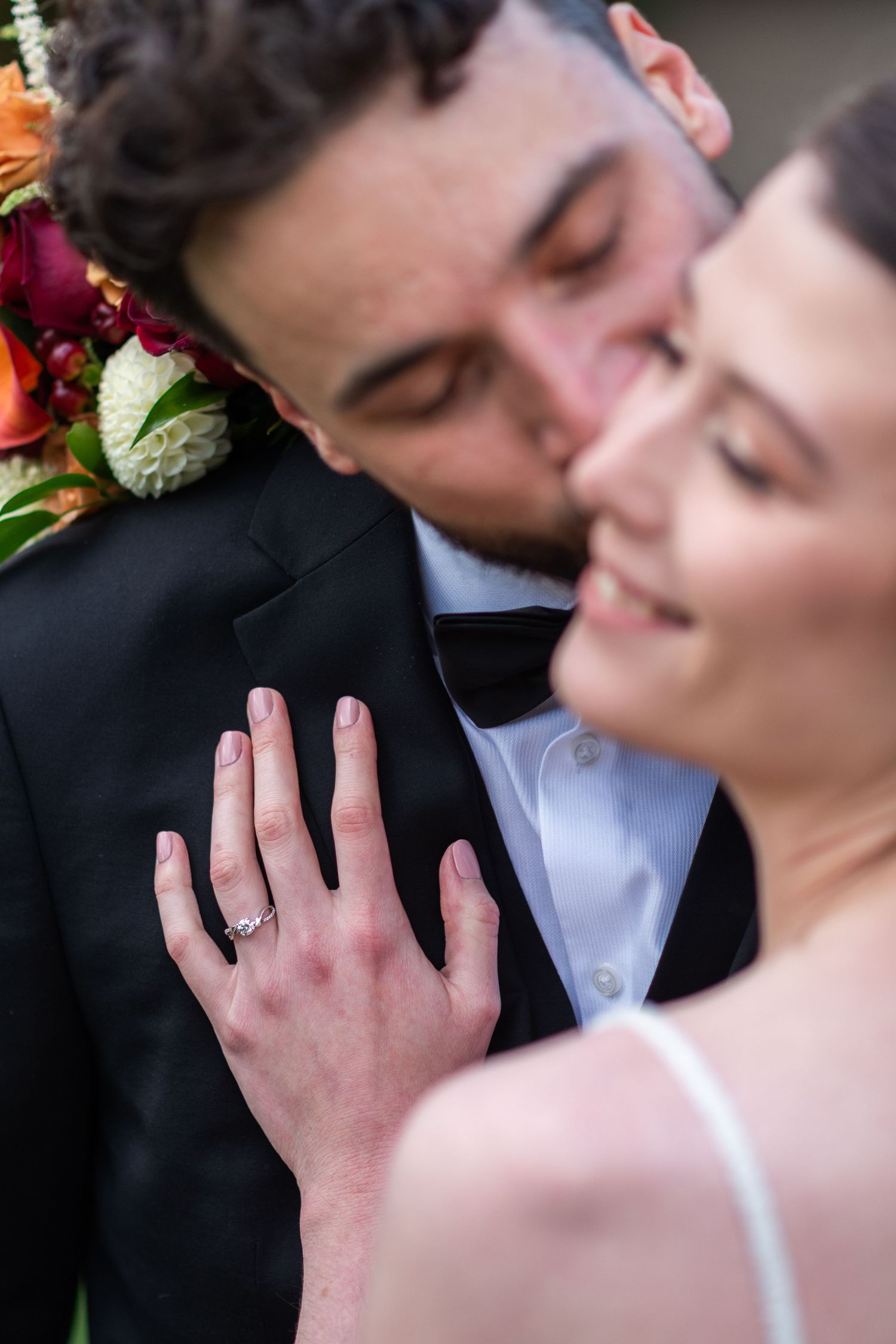 Close-up of a bride showing off her wedding ring while sharing an intimate moment with her groom.