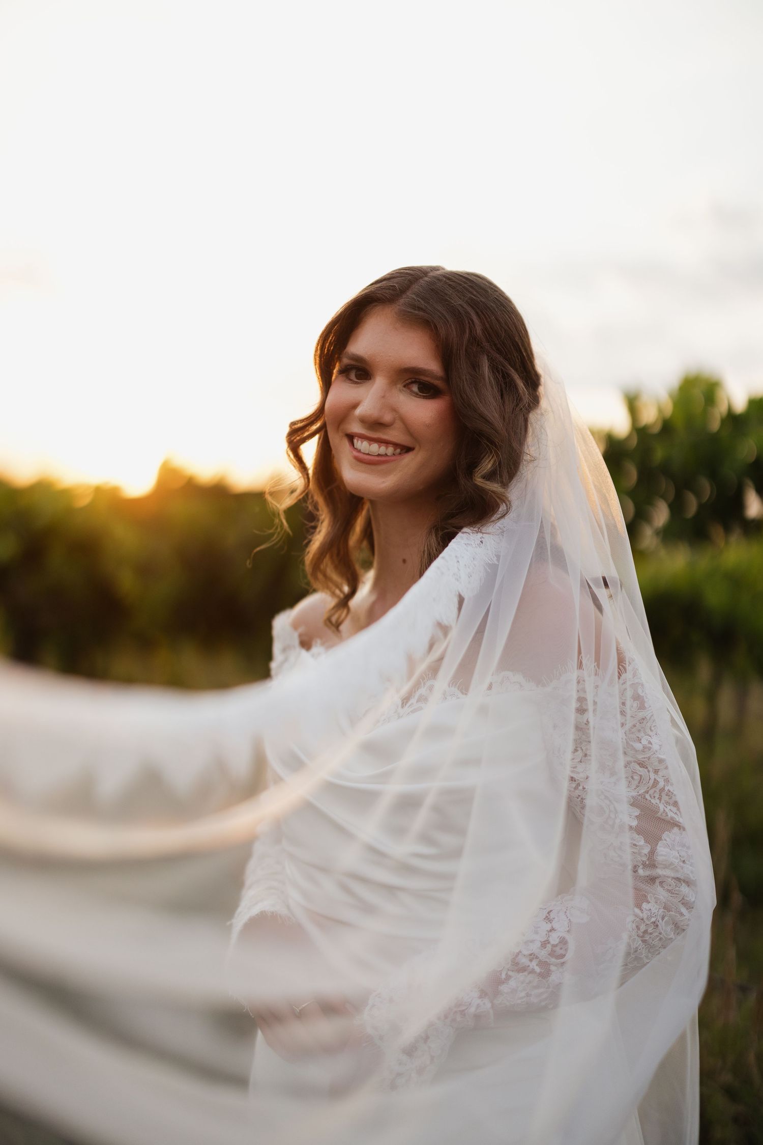 Smiling bride portrait in her wedding veil during a sunset session at Fair Haven at the Vineyards in Arkansas.