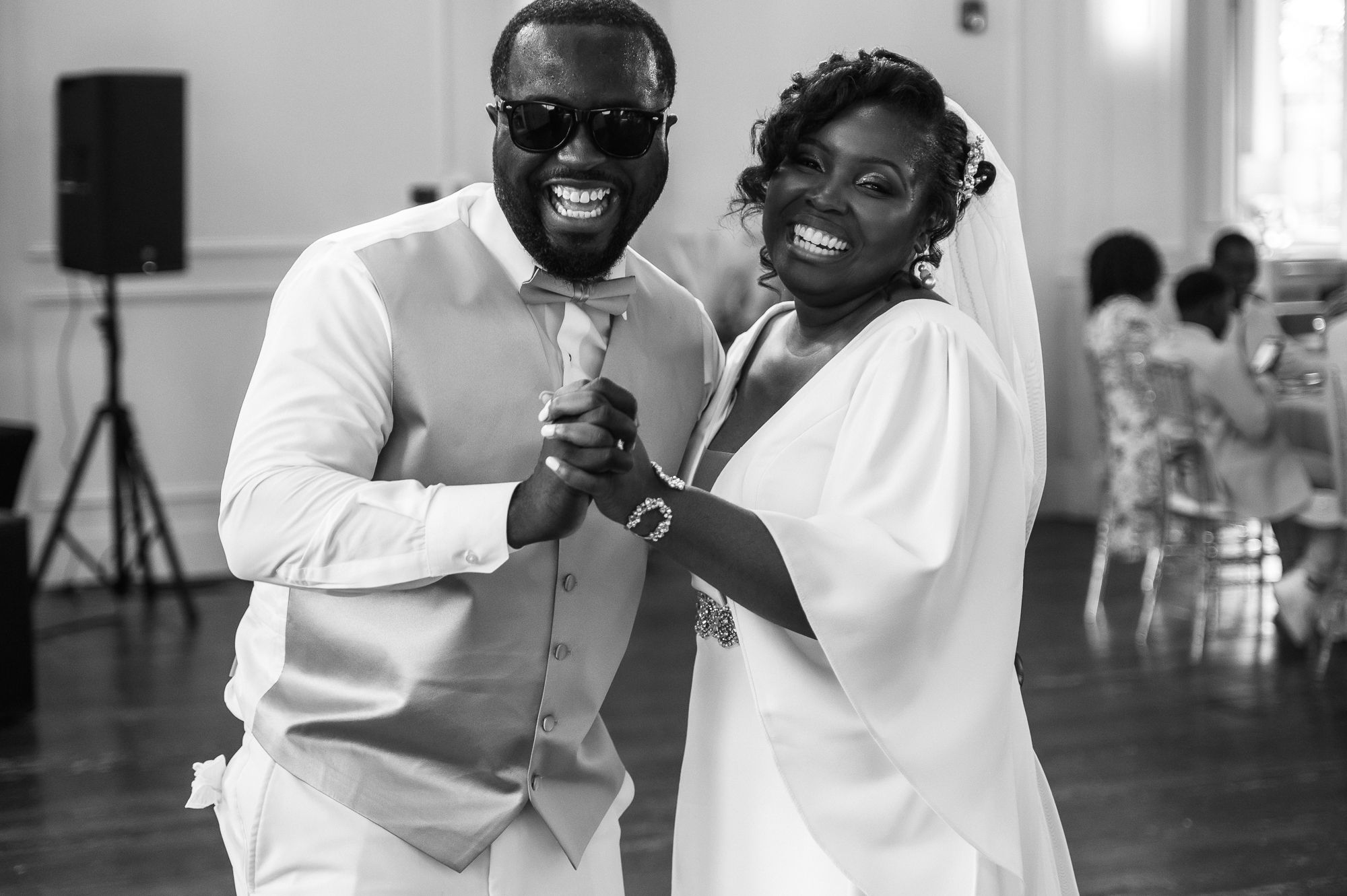 Happy newlyweds sharing their first dance in black and white wedding photo at reception.