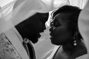 Black and white photo of a couple in wedding attire sharing an intimate moment under a veil.