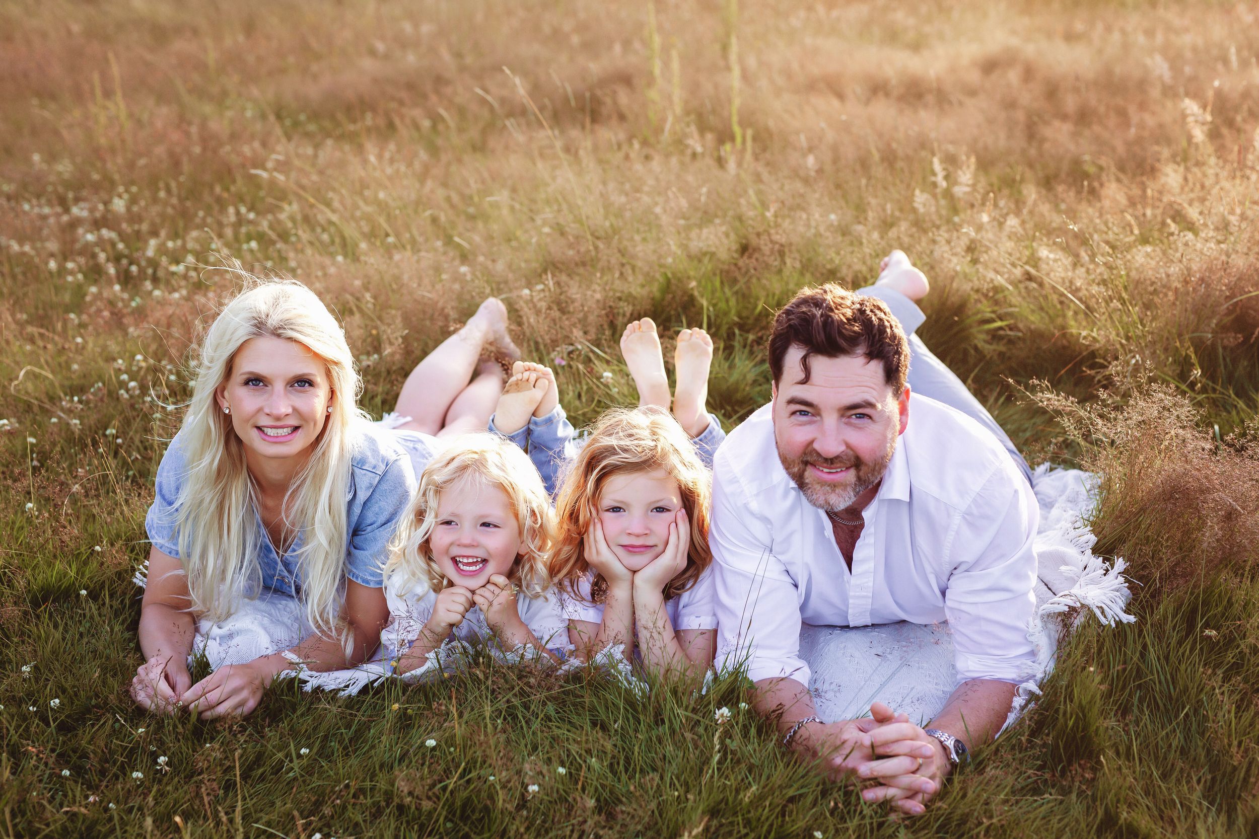 Familjefotografering i Göteborg. Mamma, pappa och två pojkar ligger på magen gräsmattan.