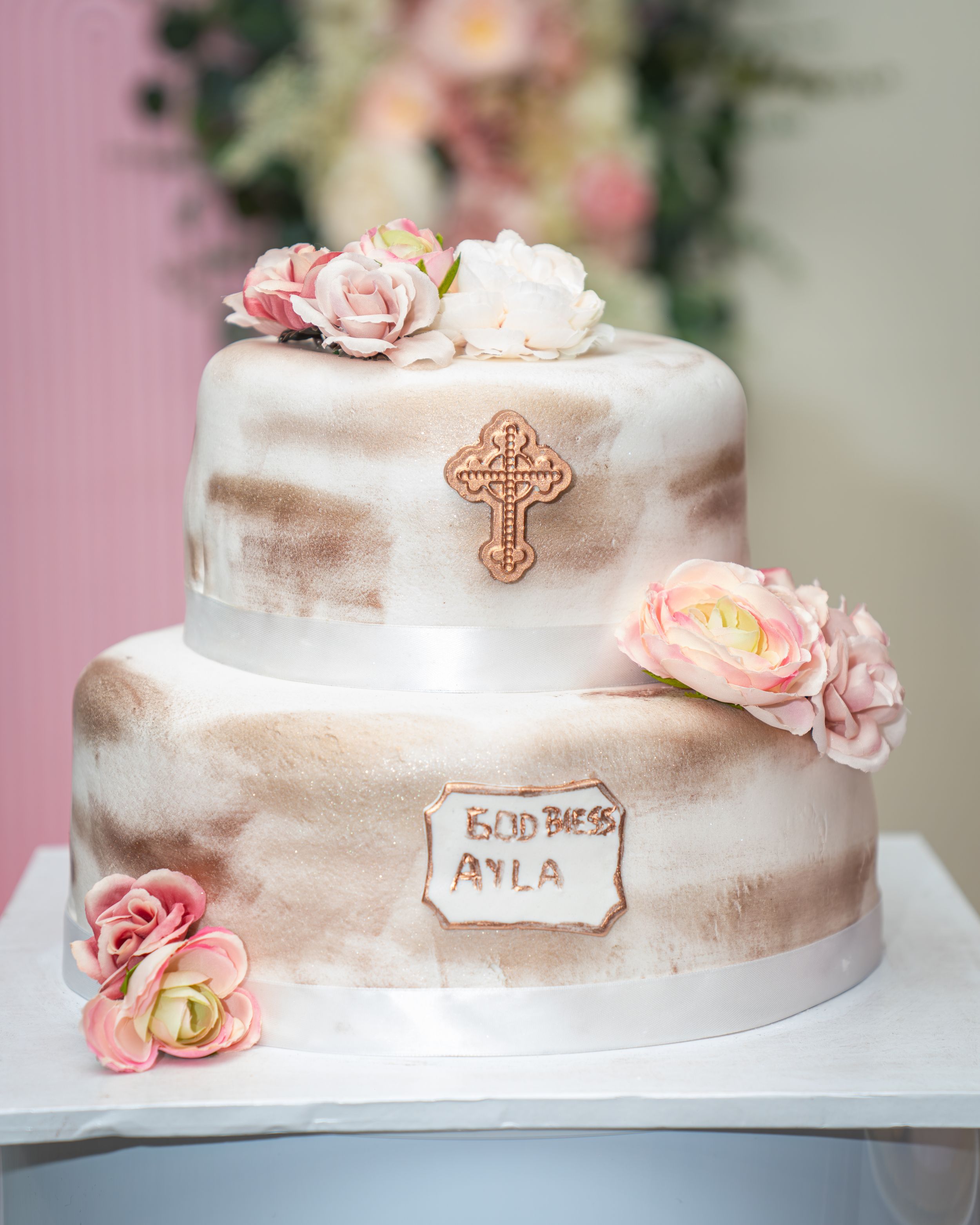 Elegant white baptism cake decorated with delicate pink roses and a gold cross on top, displayed in multiple angles.