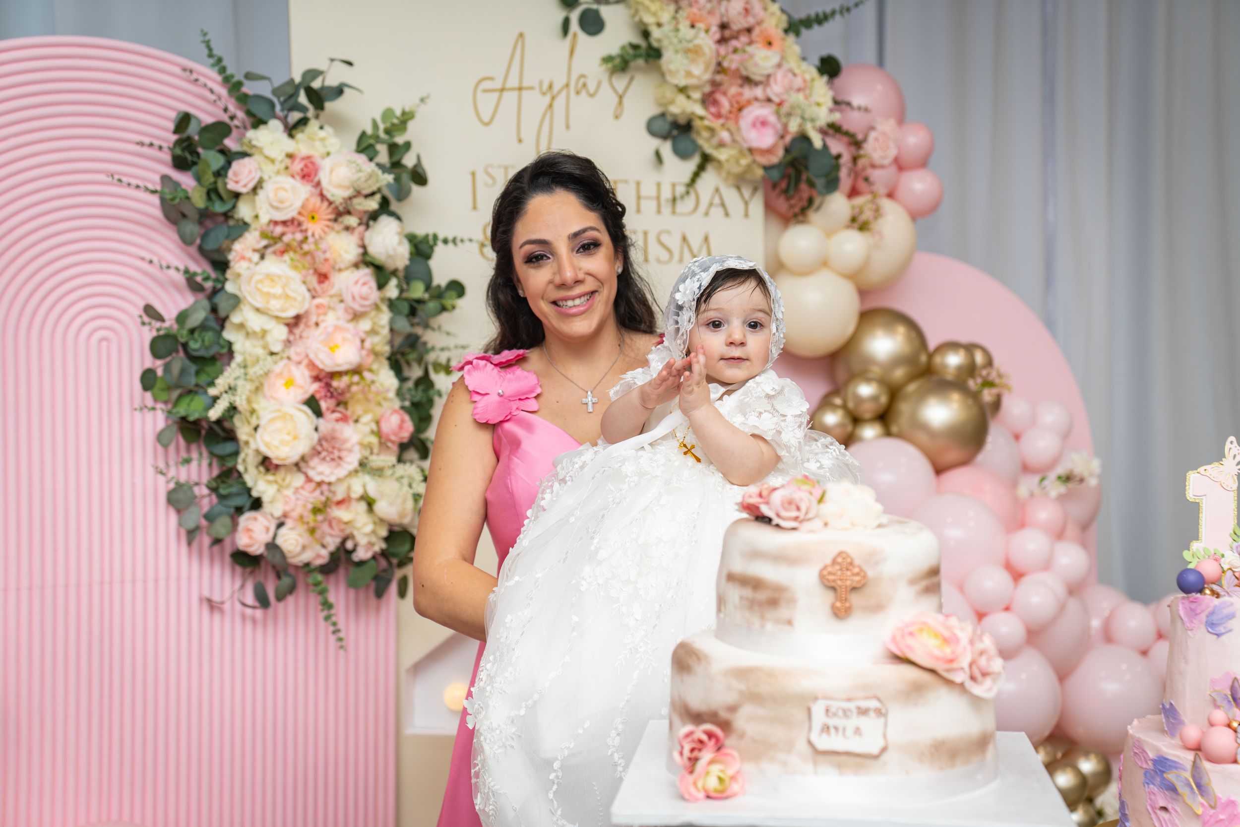 Pink and white themed baptism celebration setup with floral decorations and elegant party arrangements.