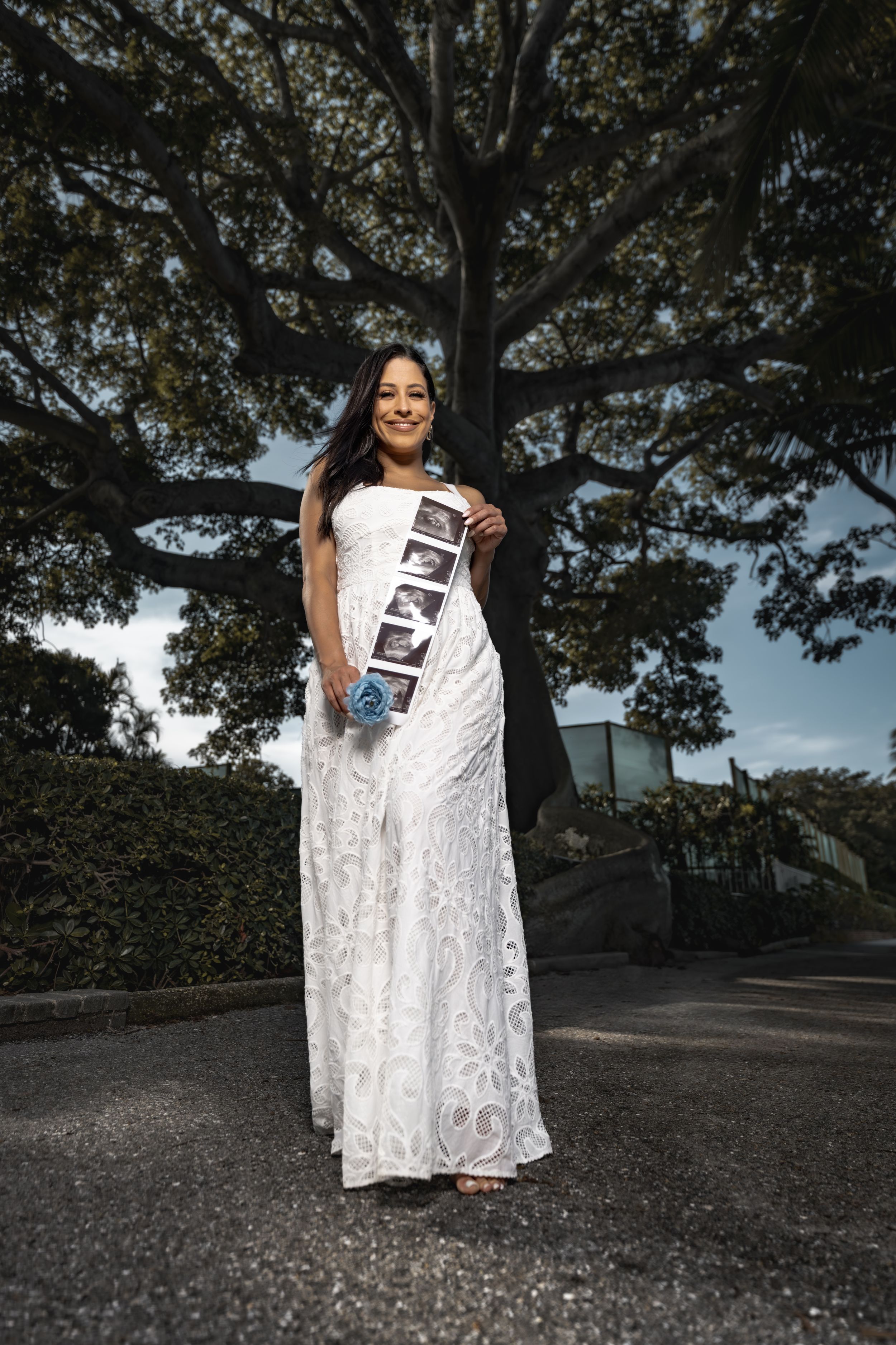 A series of photos showing someone in a white lace dress holding ultrasound photos in an outdoor setting.