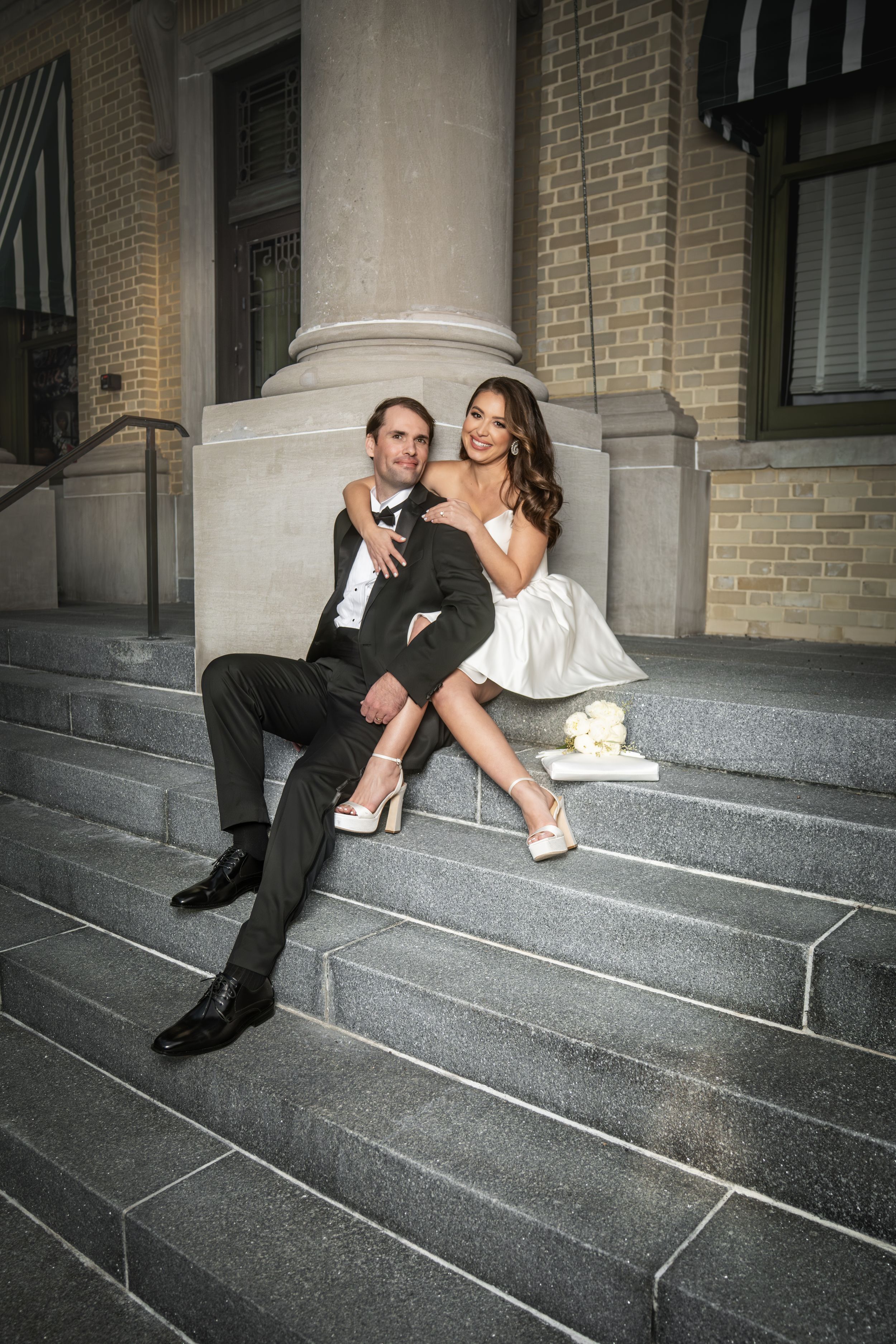 A couple in wedding attire relaxes playfully on stone steps in a sequence of candid poses.