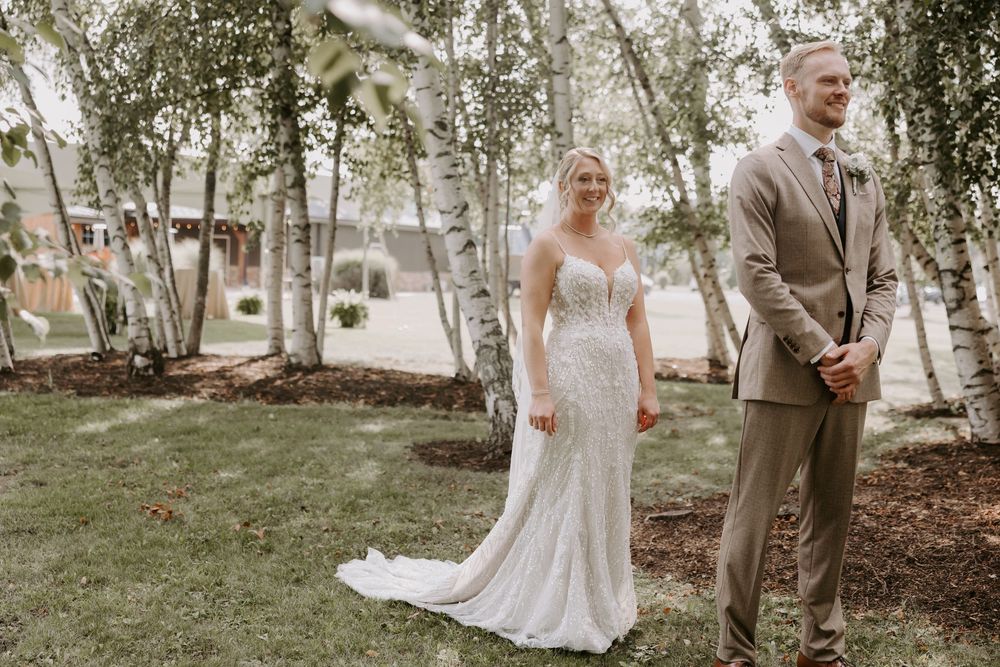 Bride and groom sharing a romantic first look moment surrounded by white birch trees.