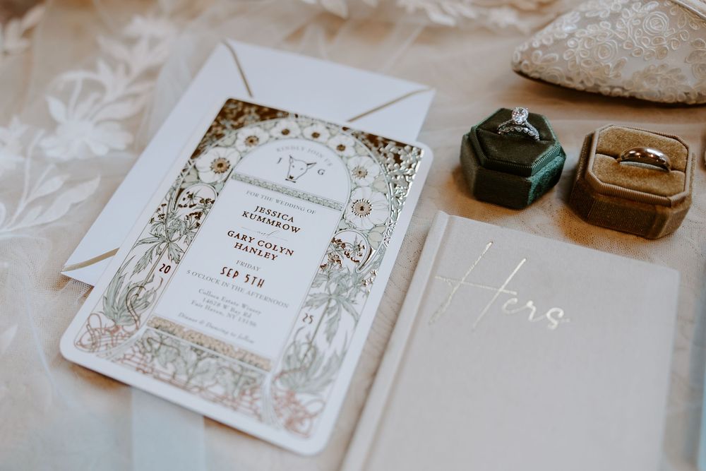 Elegant floral wedding invitation suite with green velvet ring boxes and diamond engagement ring on a soft background.