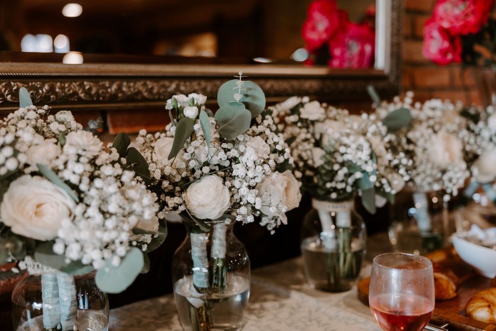 White roses, baby's breath, and eucalyptus wedding centerpieces arranged in glass vases on a table.