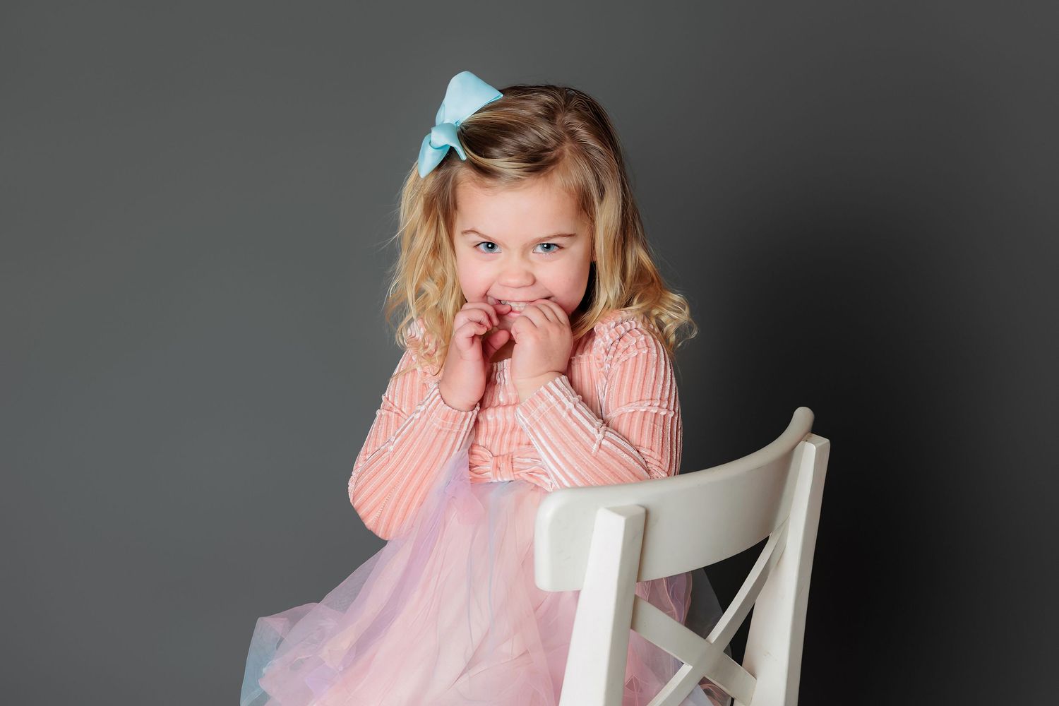 A series of connected photos showing someone in a pink sweater sitting in a white chair against a dark background.