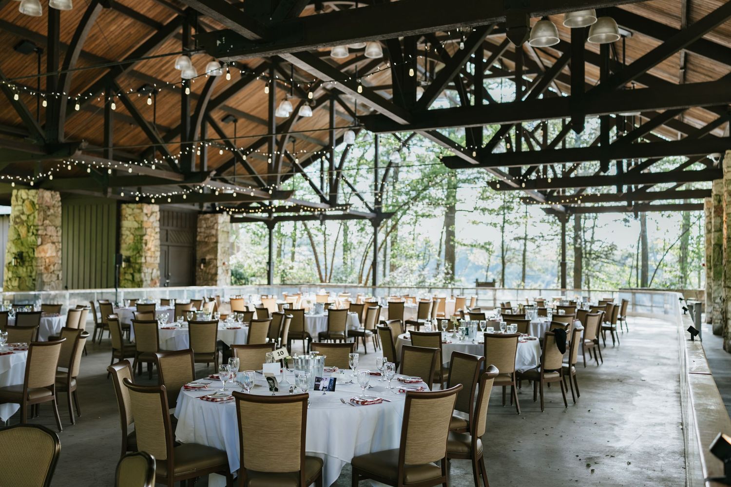 Wedding ceremony setup with white chairs on a lush green lawn facing a historic stone church under cloudy skies.