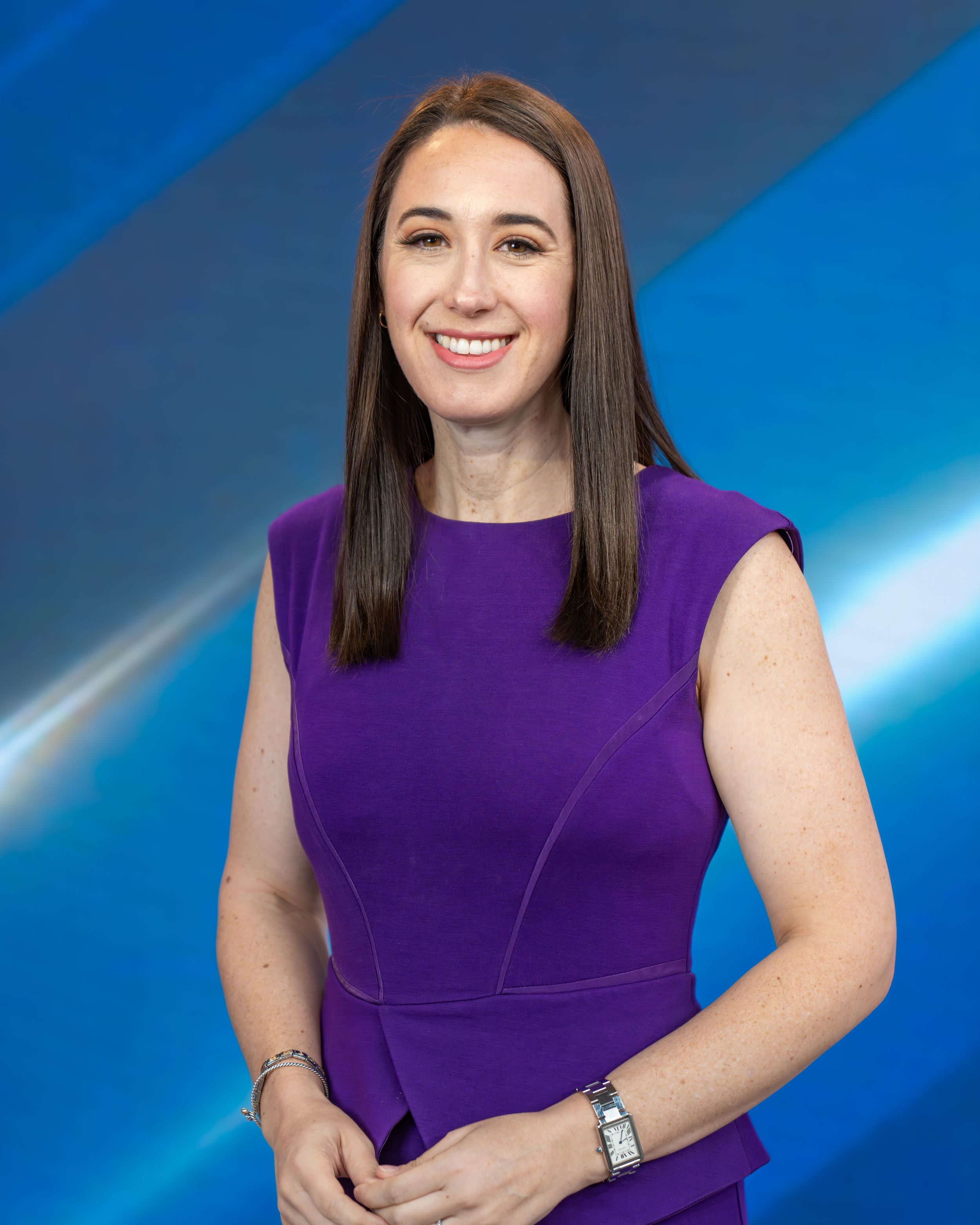 Professional headshot of a person in a sleek purple dress against a blue gradient background.