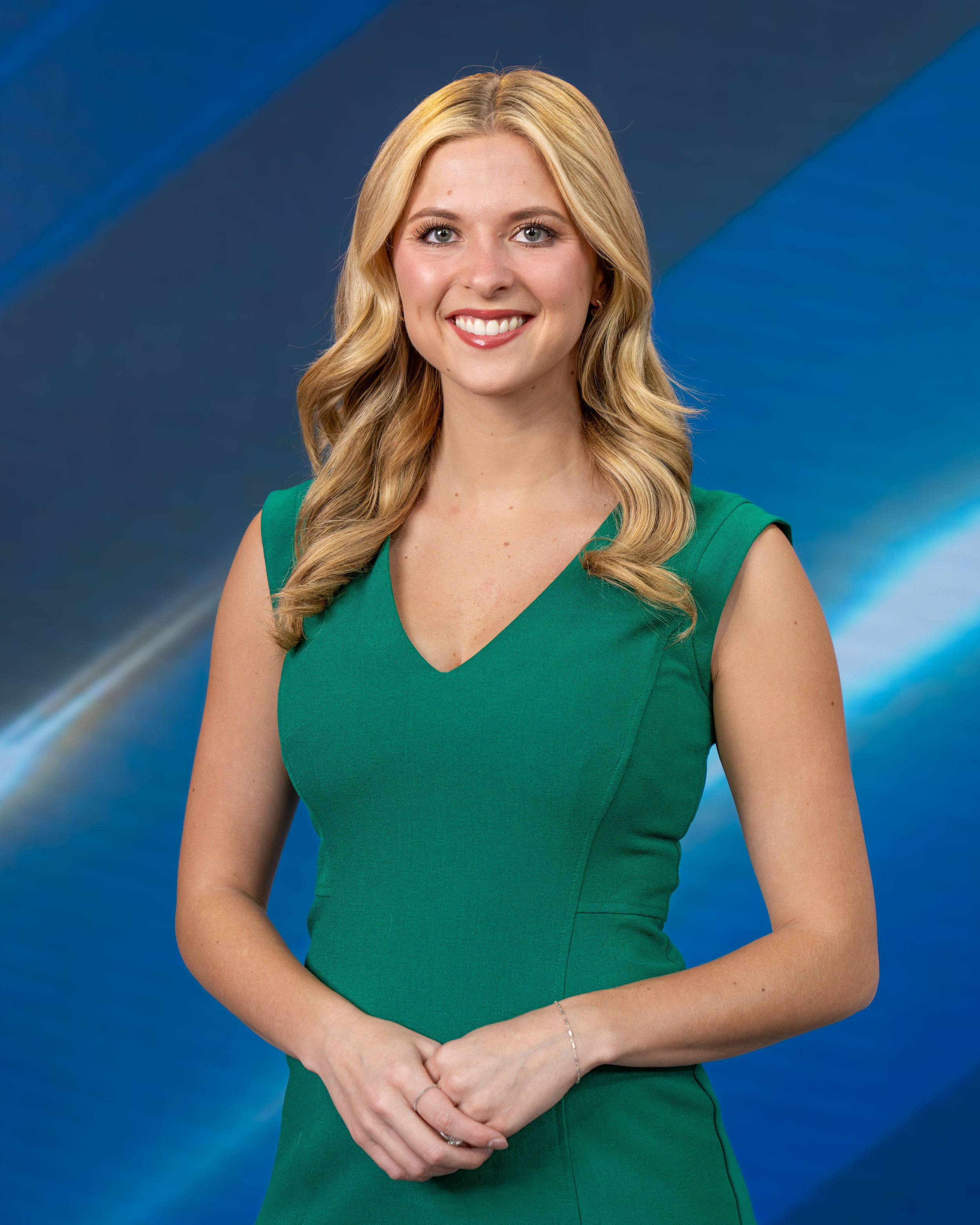 Professional headshot of someone in a green sleeveless dress against a blue gradient background.