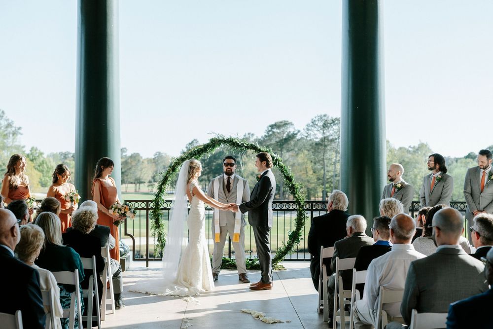 Wedding guests gathered in an elegant indoor venue with large windows overlooking a scenic landscape during a celebration.