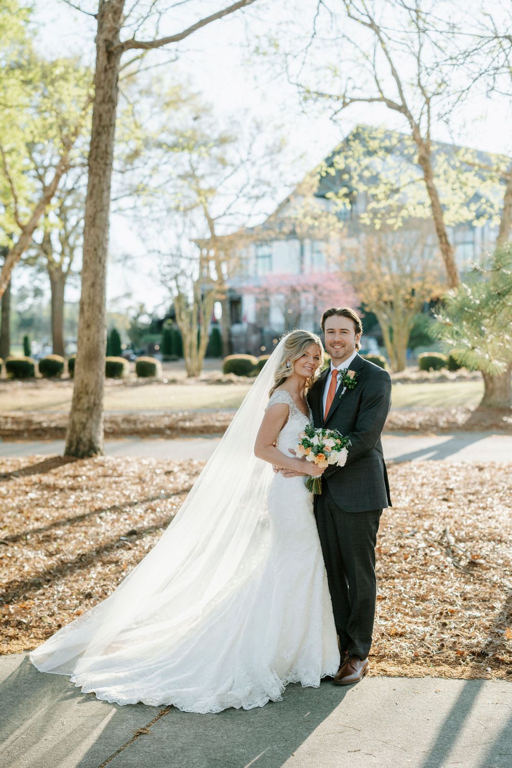 A romantic wedding photo series showing a couple embracing outdoors among trees on a sunny autumn day.