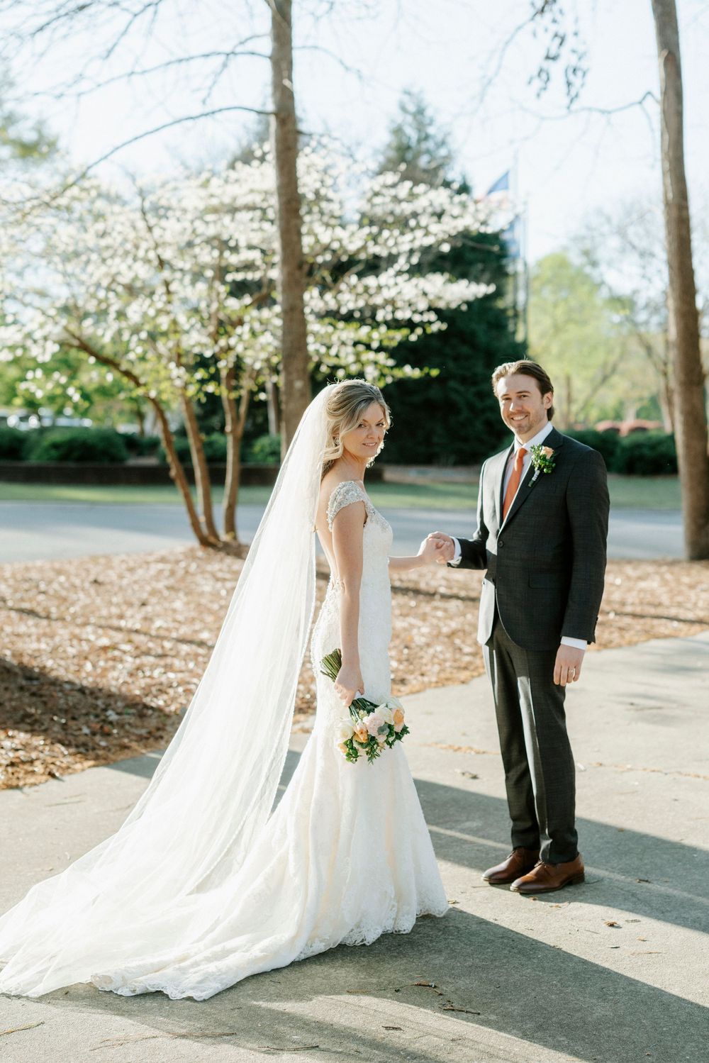 A romantic wedding couple shares intimate moments in a series of outdoor portraits under blooming spring trees.