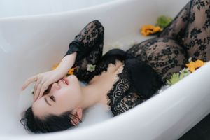 Artistic bathtub portrait with black lace and yellow flower accents.以黑色蕾絲和黃色花朵點綴的藝術浴缸肖像。