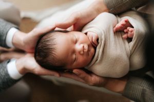 Peaceful newborn baby swaddled in neutral tones during intimate lifestyle photoshoot.在溫馨的生活照拍攝中，一位寧靜的新生兒被包裹在色調柔和的襁褓中。