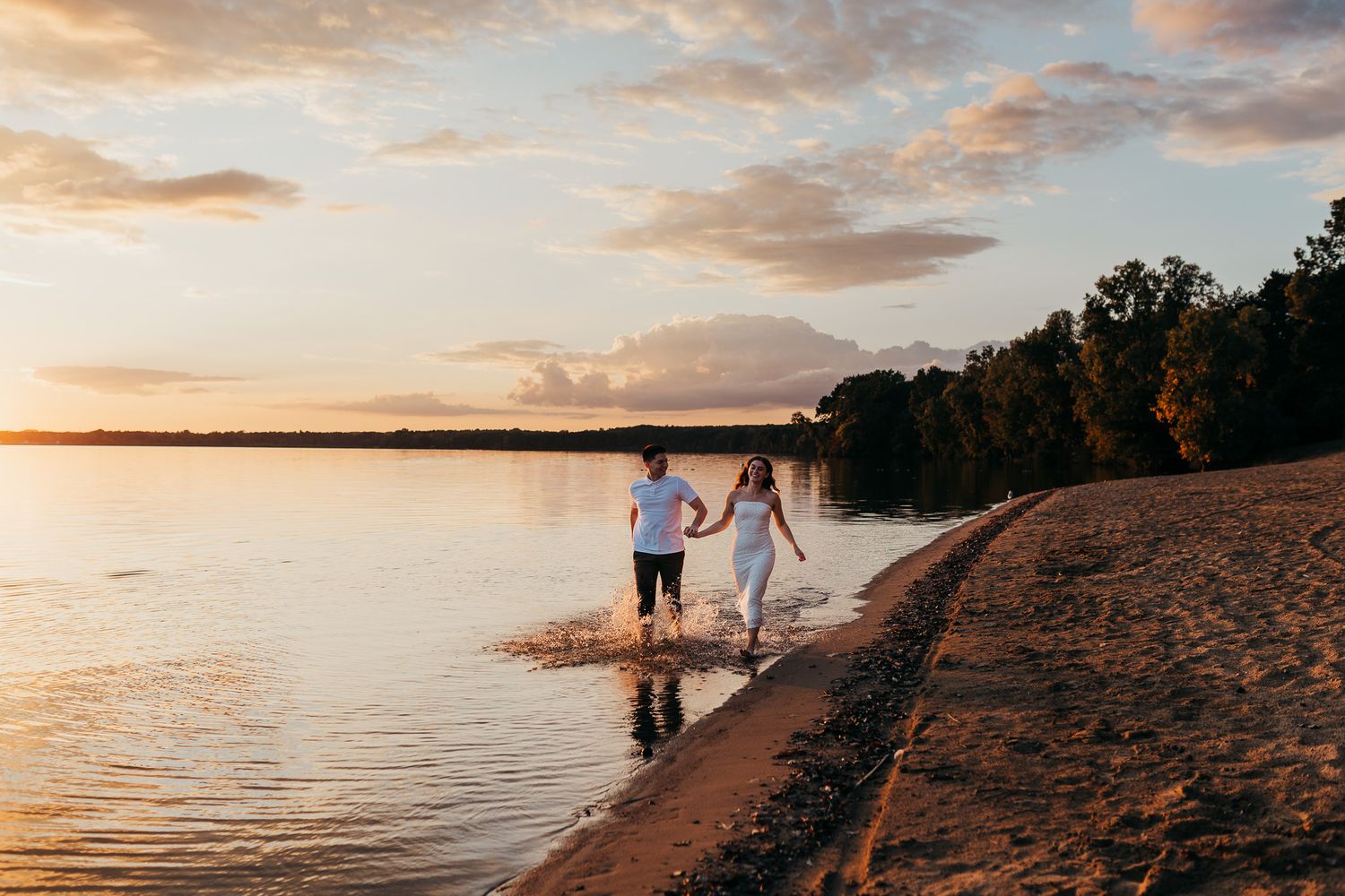 Silhouetted figures walk along a scenic beach path during a vibrant orange and pink sunset over the water.