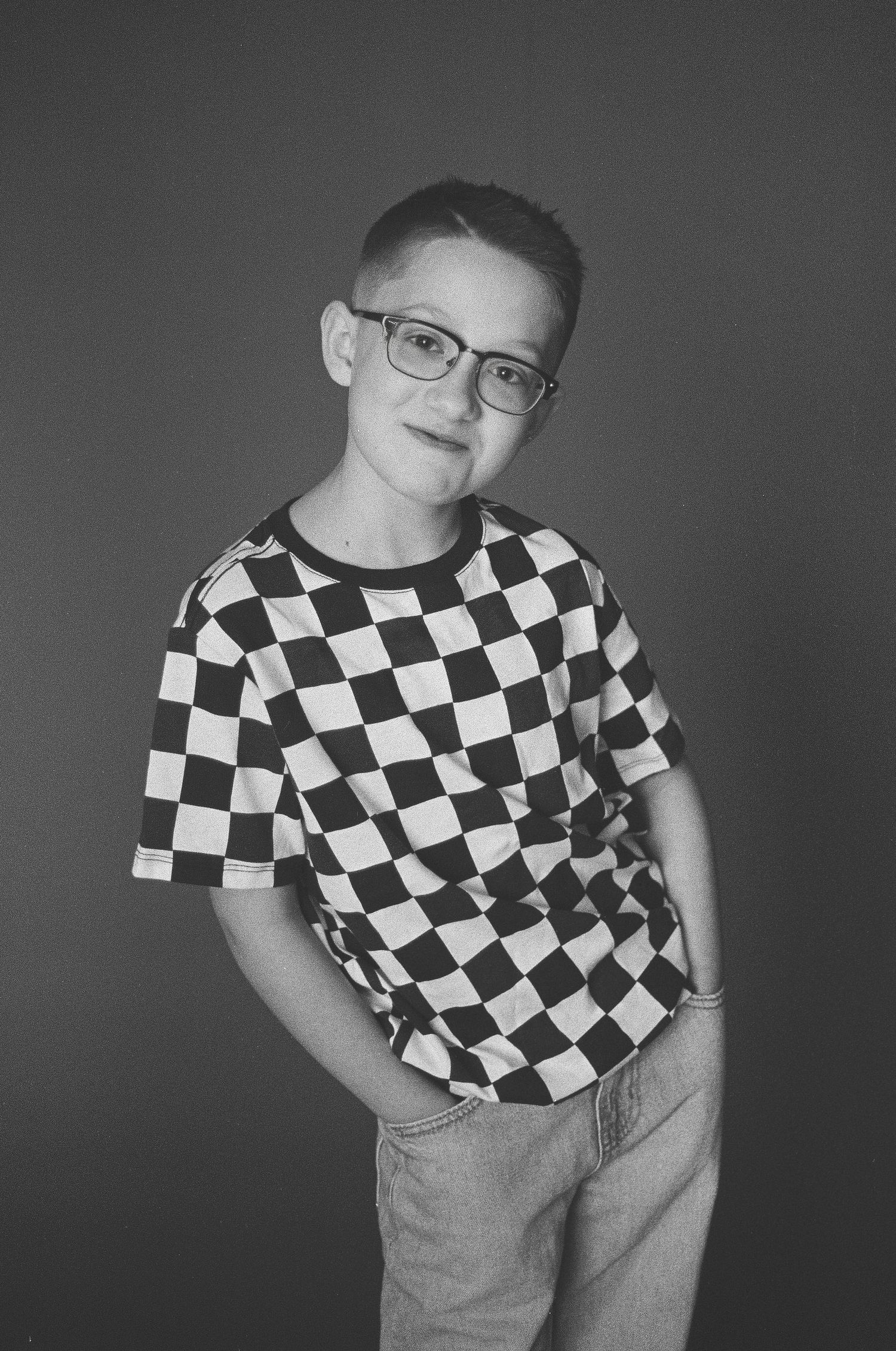 A series of black and white photos showing someone wearing a checkered t-shirt and jeans in different cropped poses.