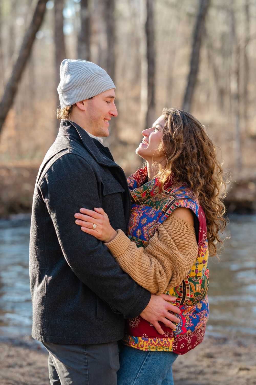 A couple embraces on a sandy riverbank in winter, sharing tender moments across multiple romantic poses.