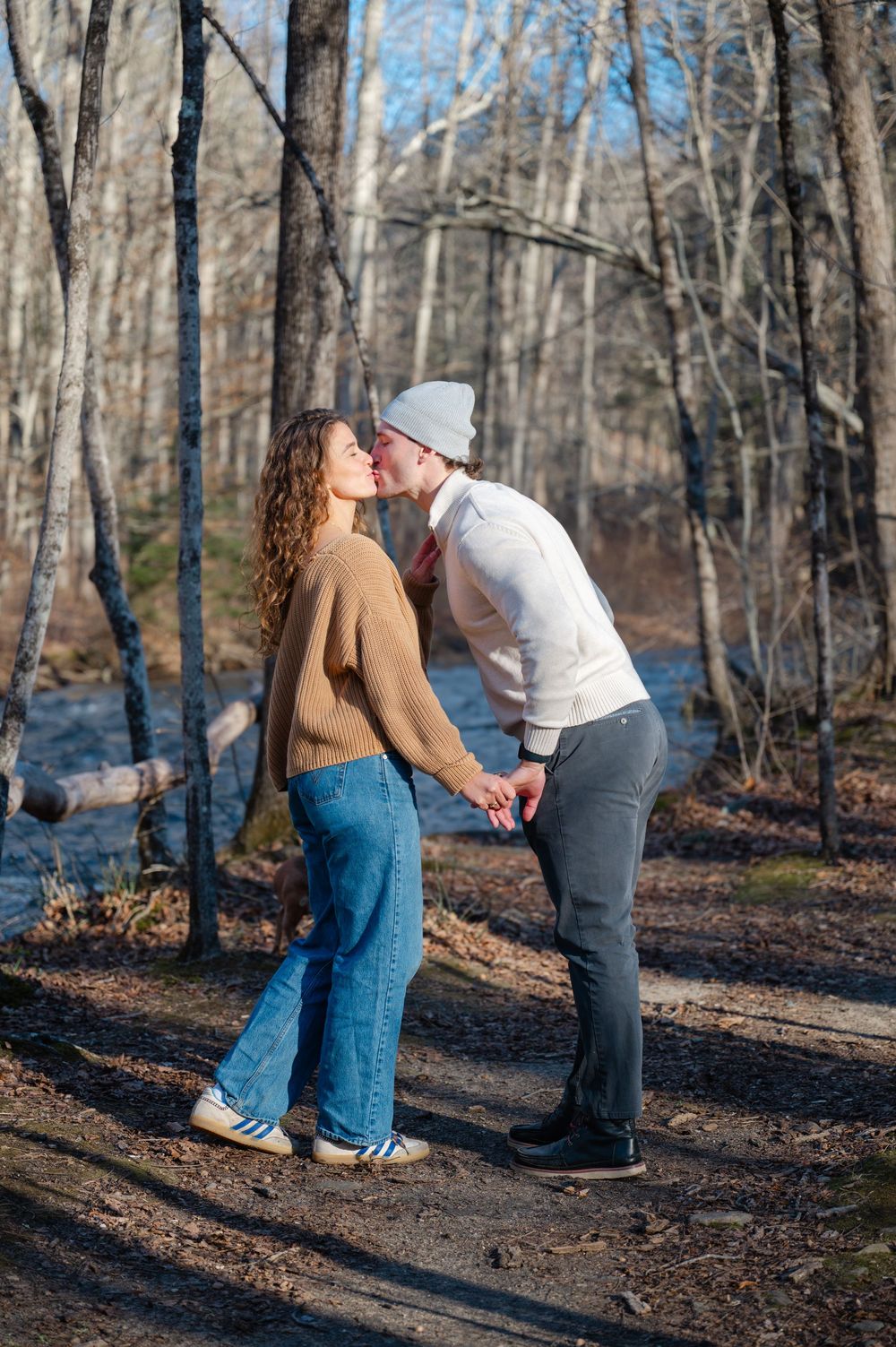 A couple shares a romantic moment during a marriage proposal in a winter forest setting.