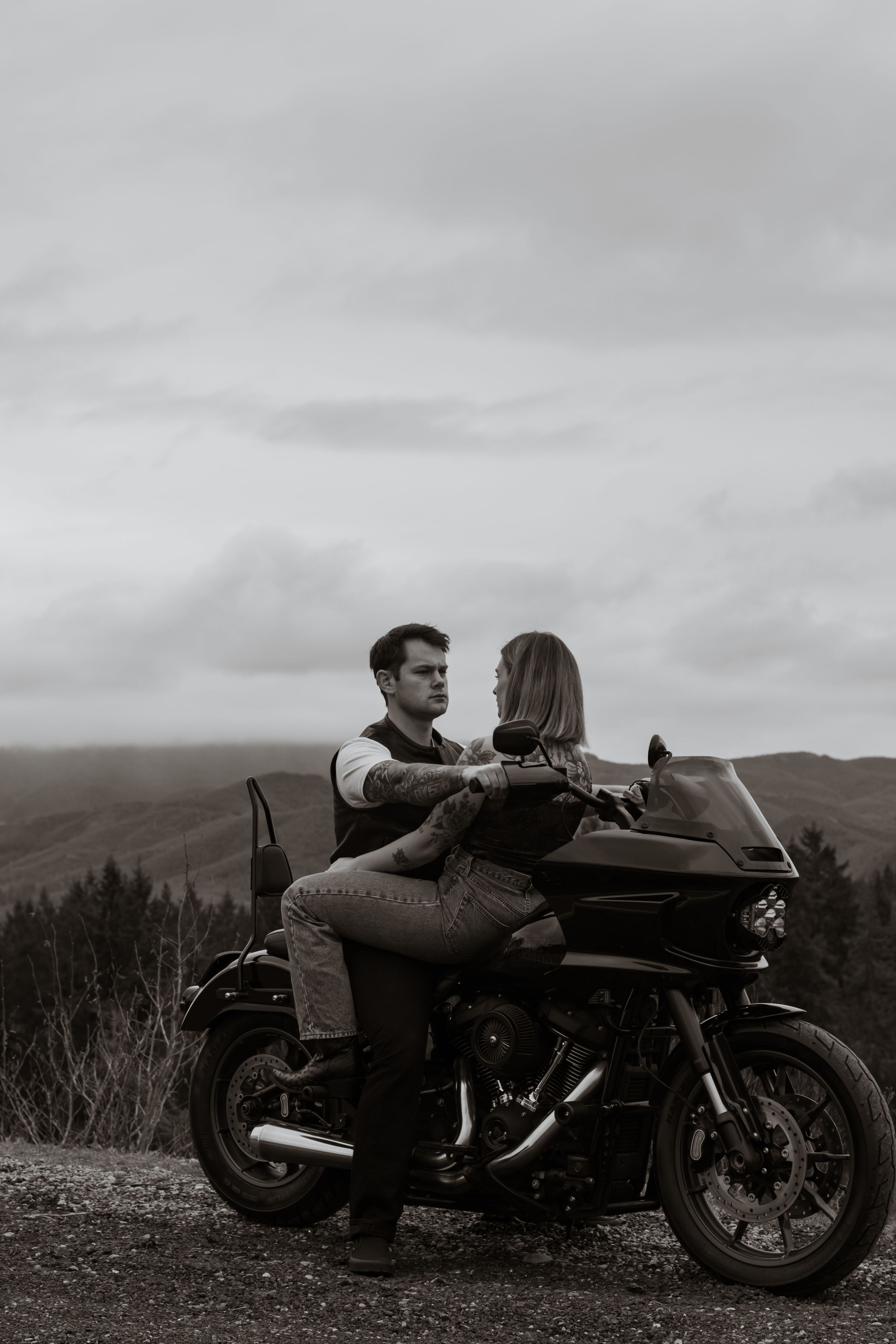 Black and white photo of a couple facing each other intimately while seated on a motorcycle during a photoshoot in yelm washington hills