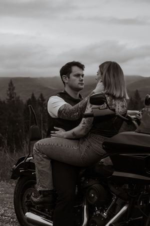 Black and white photo of a tattooed couple sharing an intimate moment while sitting on a motorcycle taken by yelm washington photographer