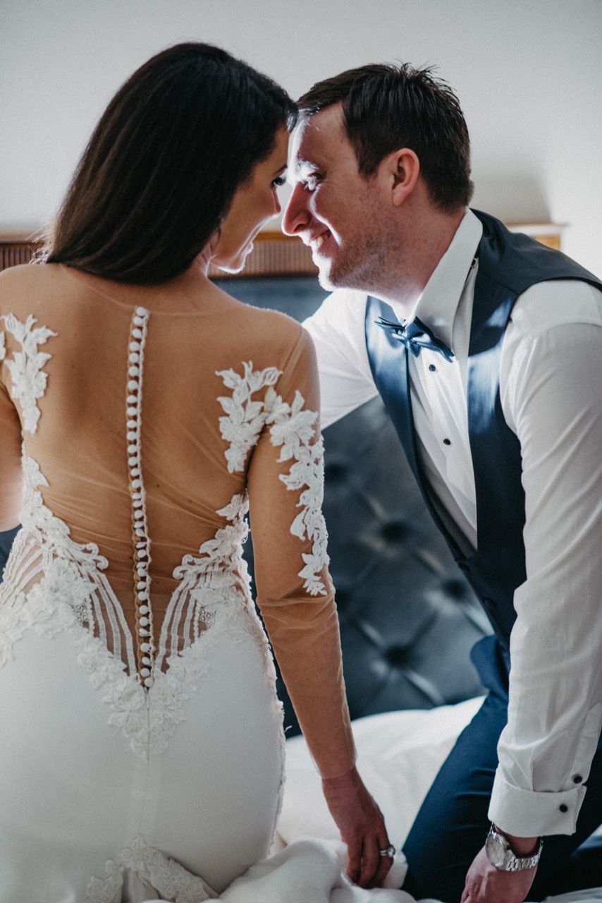 Wedding dress detail showing delicate lace appliques on sheer fabric during intimate moment.