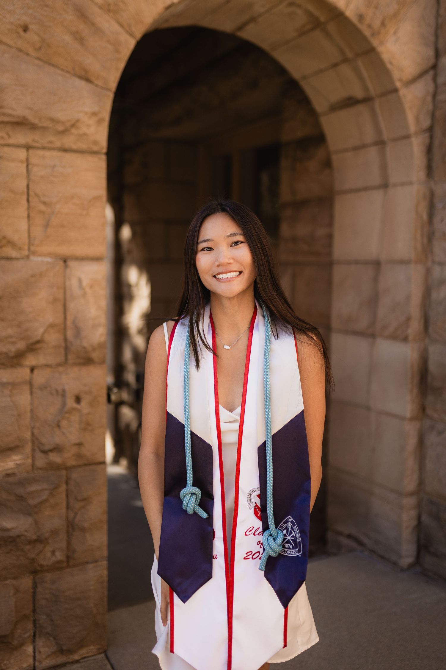 A Colorado School of Mines graduation photo series showing a graduate in traditional academic regalia posing in a stone archway corridor.