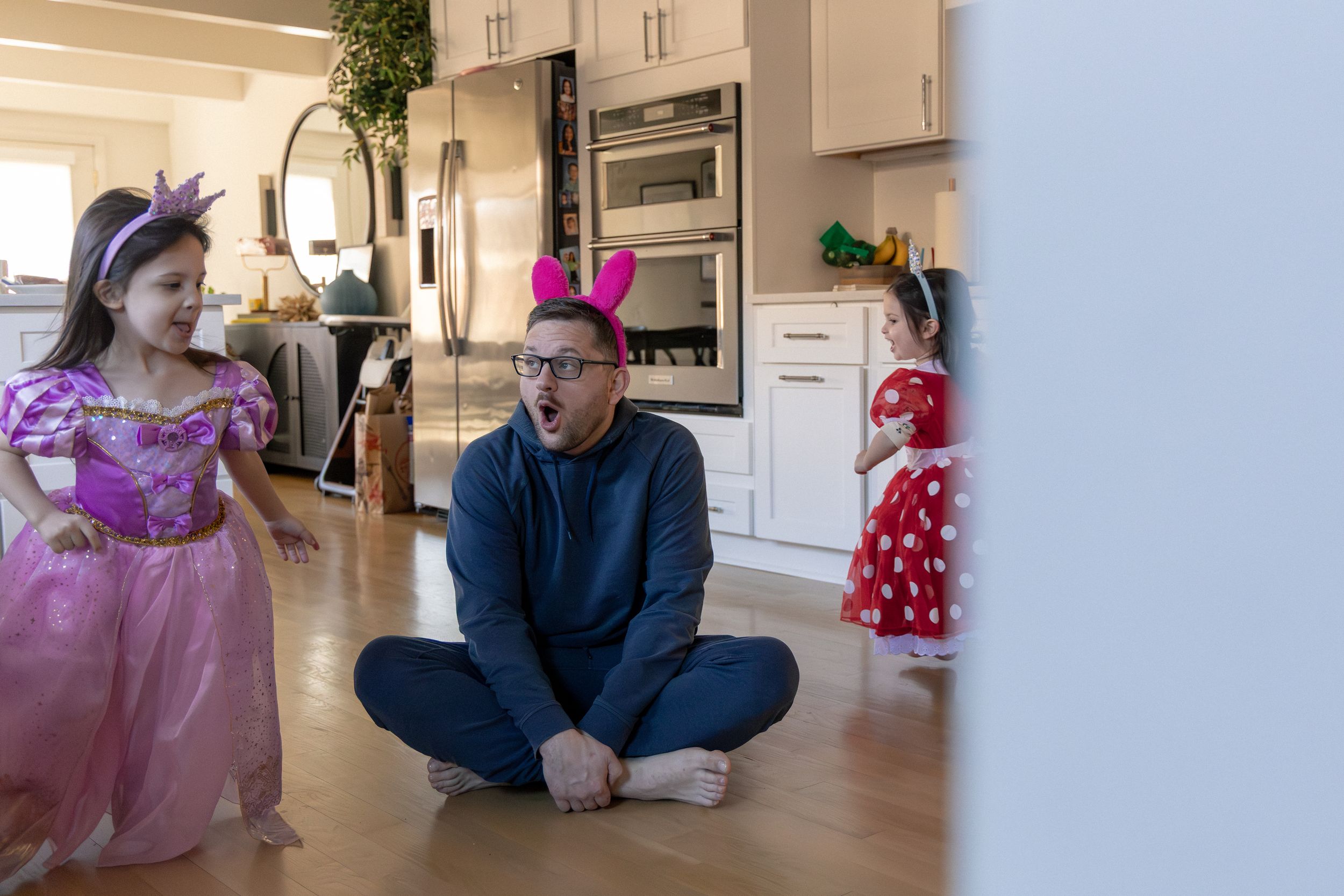 A family spends quality time together in a bright modern living room with pink and purple decorations.