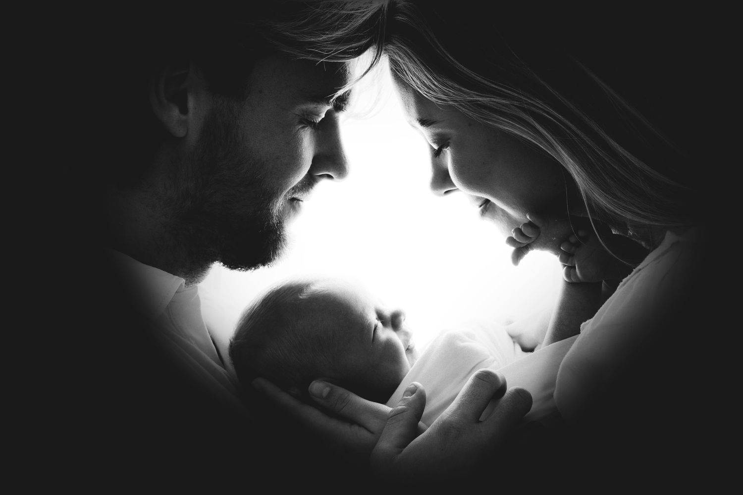 A series of intimate black and white photographs showing tender moments between a couple with a newborn baby.