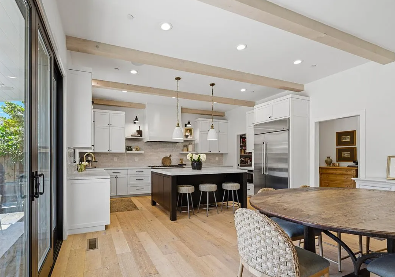 Modern open concept living room with white walls, hardwood floors, fireplace and large windows overlooking water views.