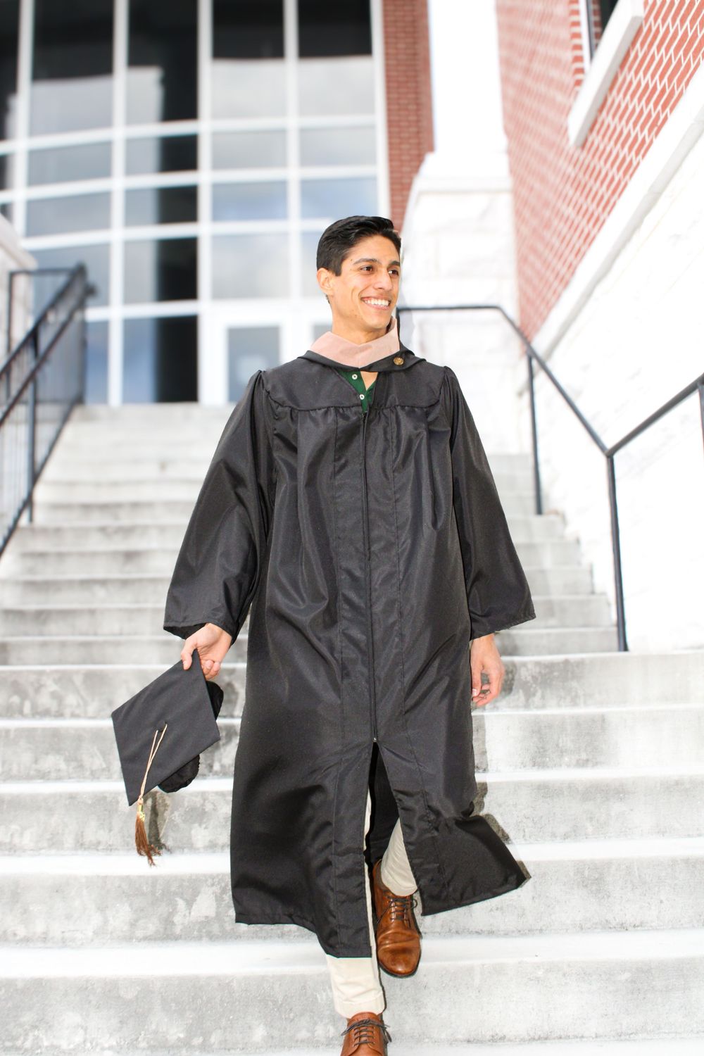 man walking down stairs in graduation clothes